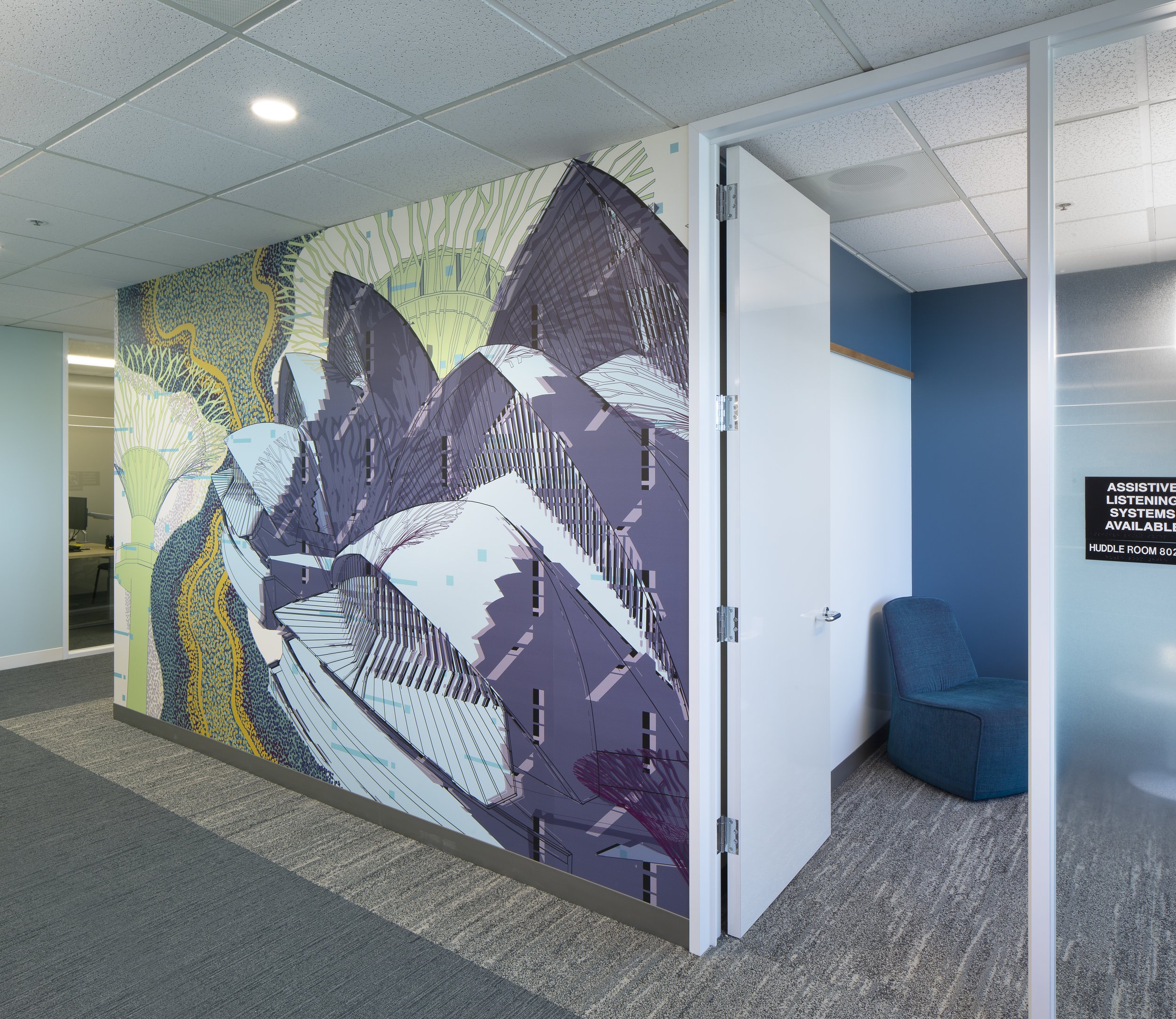 A partially open doorway to a modern office space or reception area with a colorful abstract mural on the wall beside it. The mural features stylized mountain peaks with a digital or technological design. 