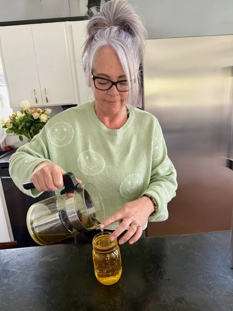 women pouring calendula infused jojoba oil to make handcrafted skin care