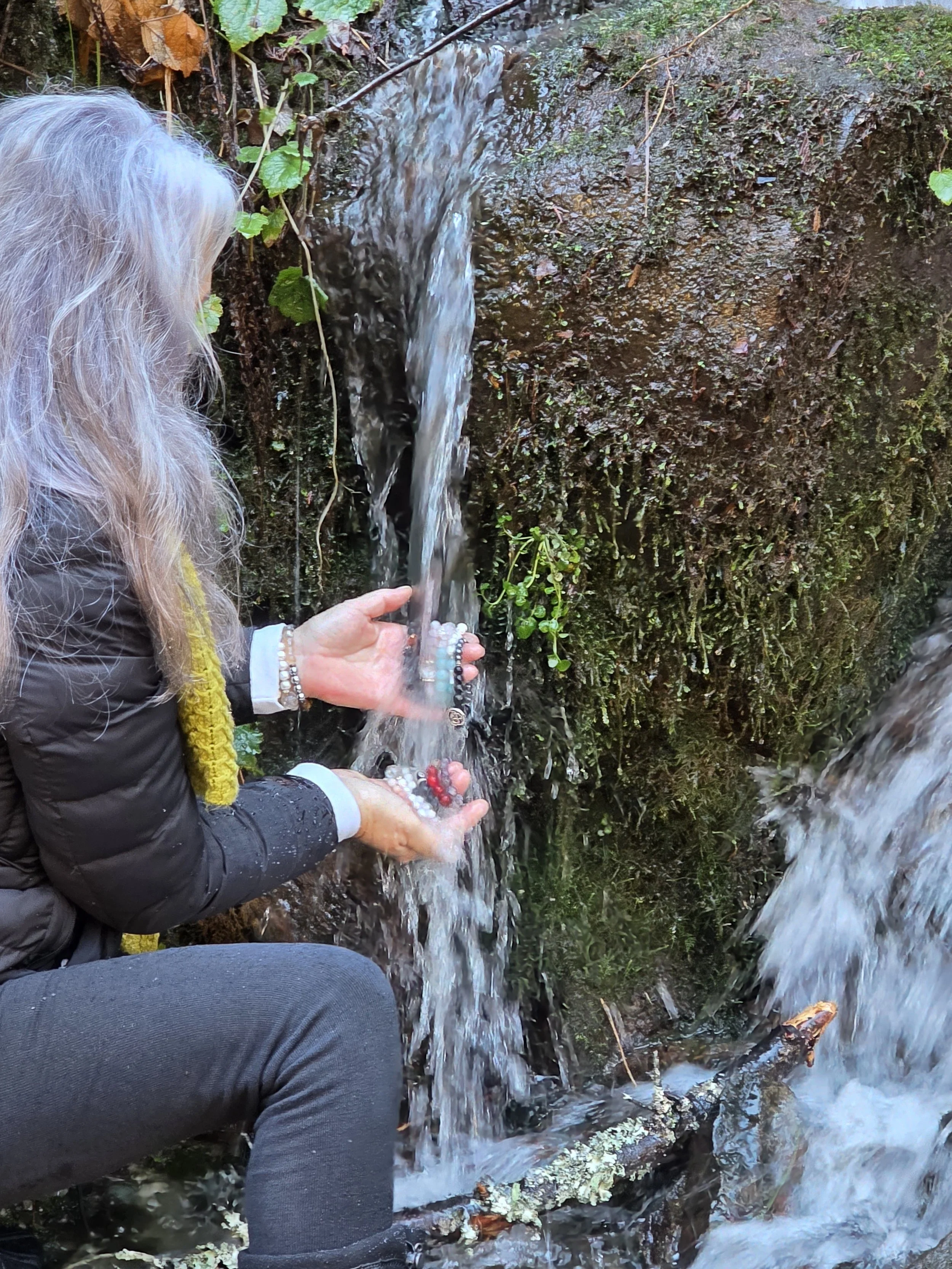 women cleansing handcrafted natural gem stone bracelets in waterfall
