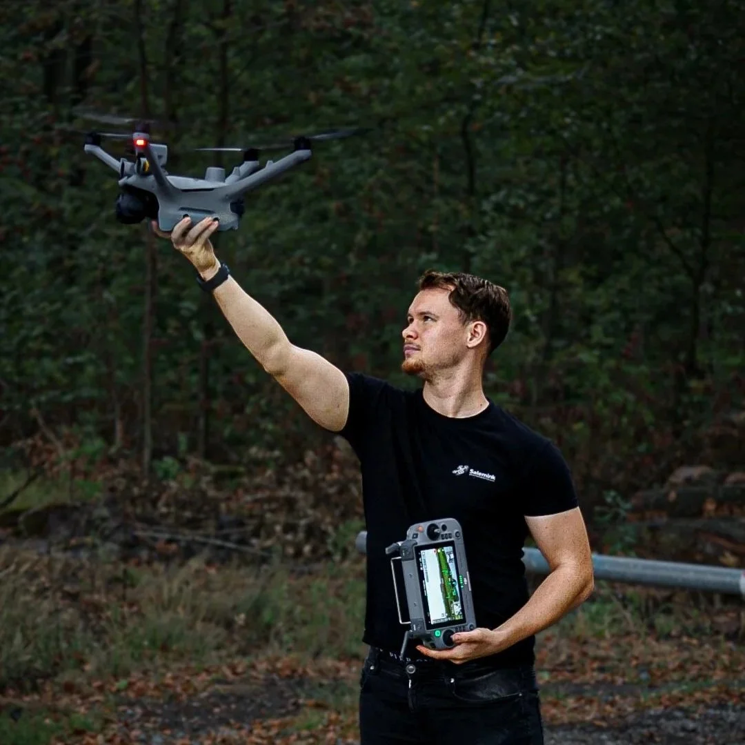 Mann bedient eine Drohne im Wald mit einem Steuergerät in der Hand
