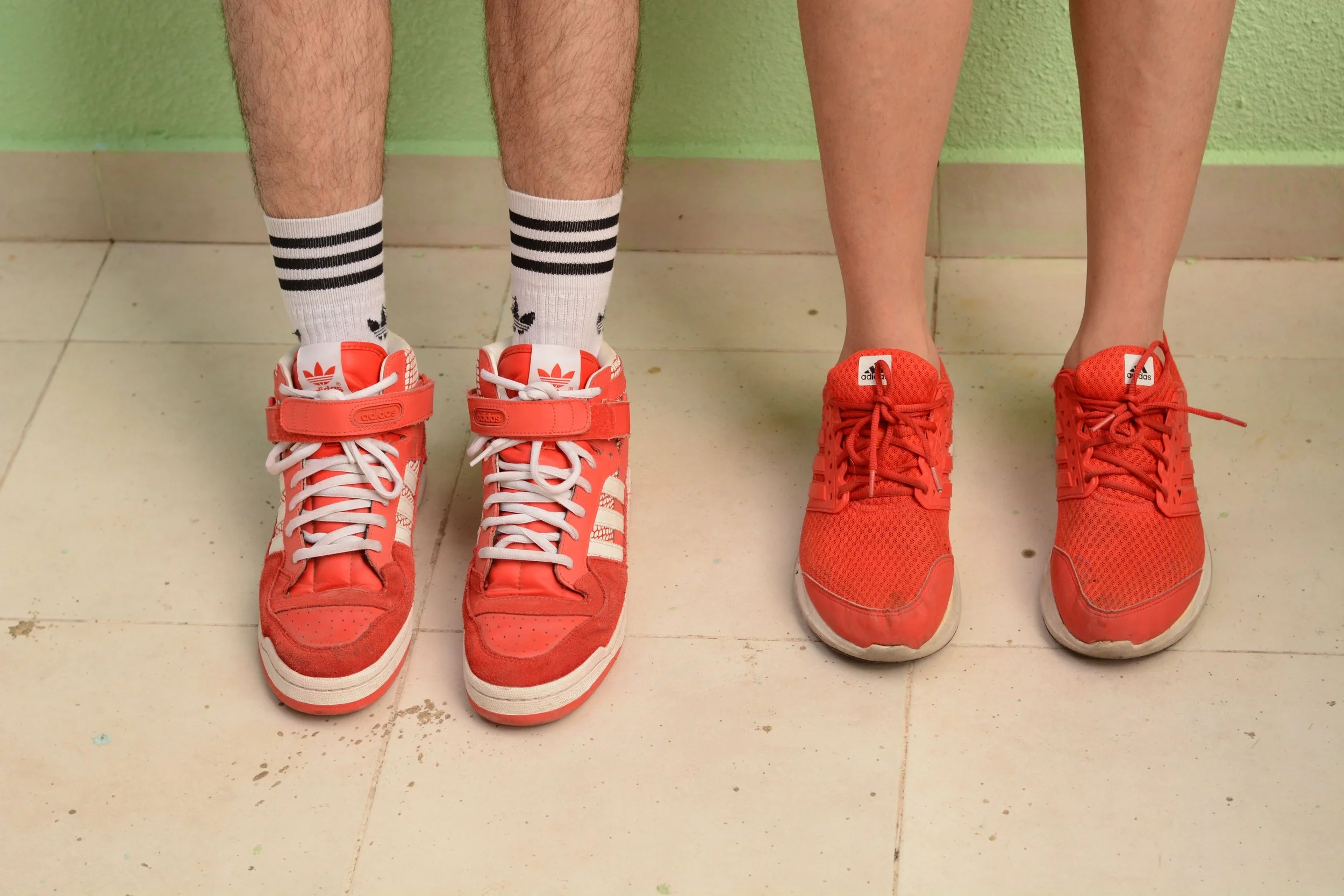 two people with only legs showing both wearing orange adidas