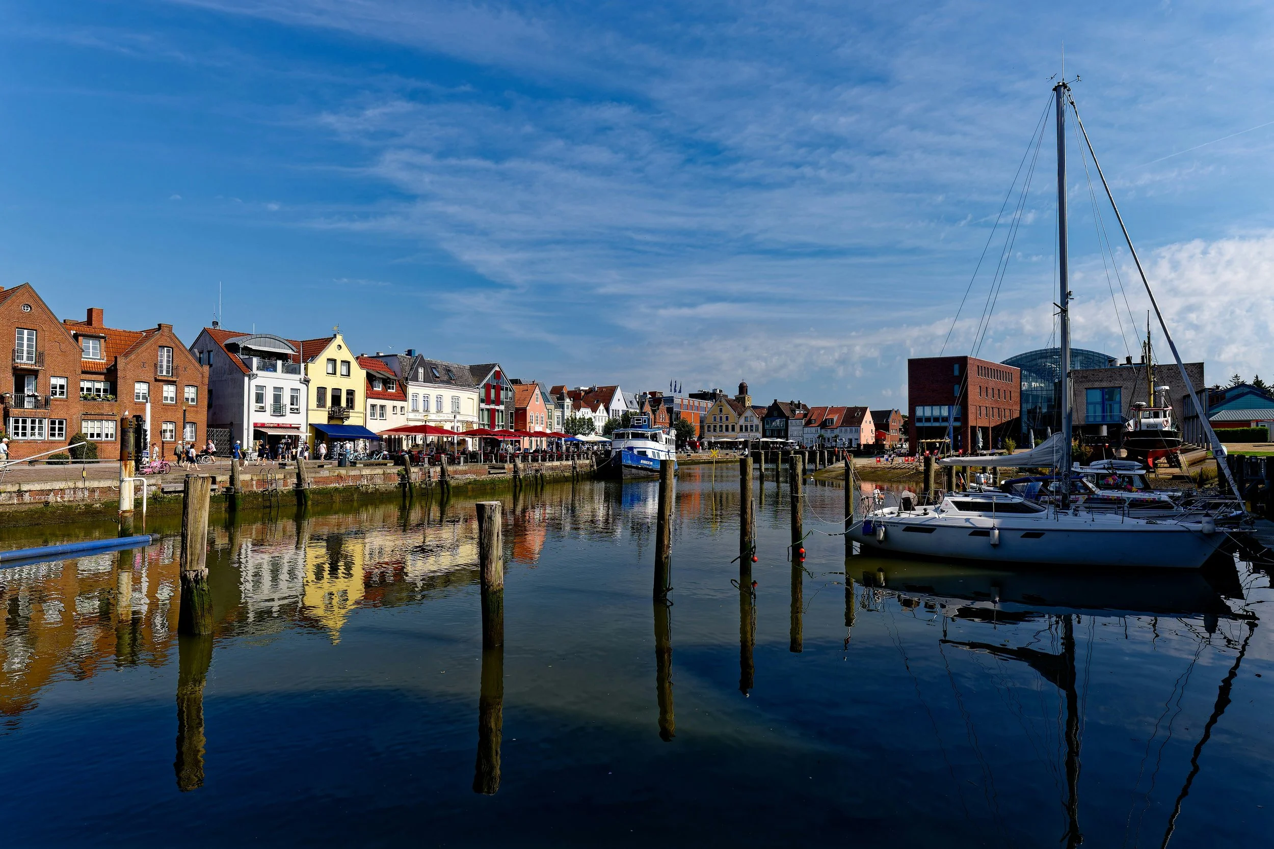 Colorful buildings and boats along a harbor with calm water and blue sky.