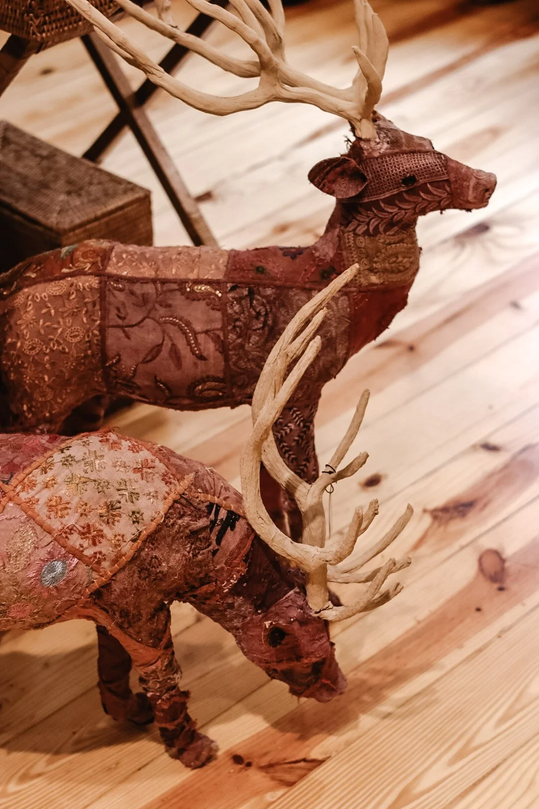 Decorative fabric reindeer figurines with antlers on wooden floor.