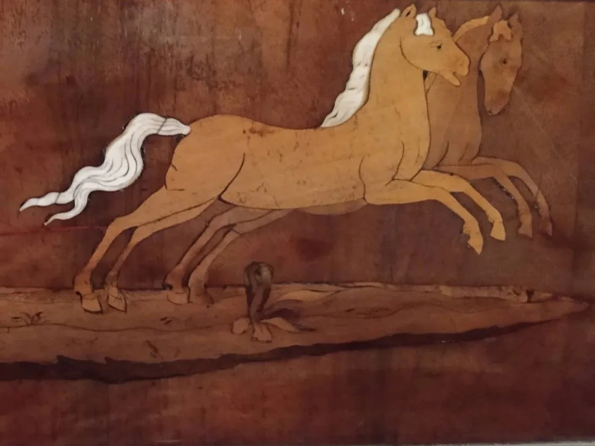 Wooden wall art depicting two horses running, with one horse having a white mane and tail, painted on a wooden background.