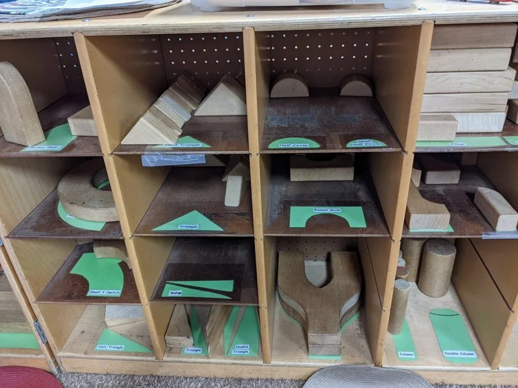 Wooden shelves with various cutout shapes and labeled green paper inserts.