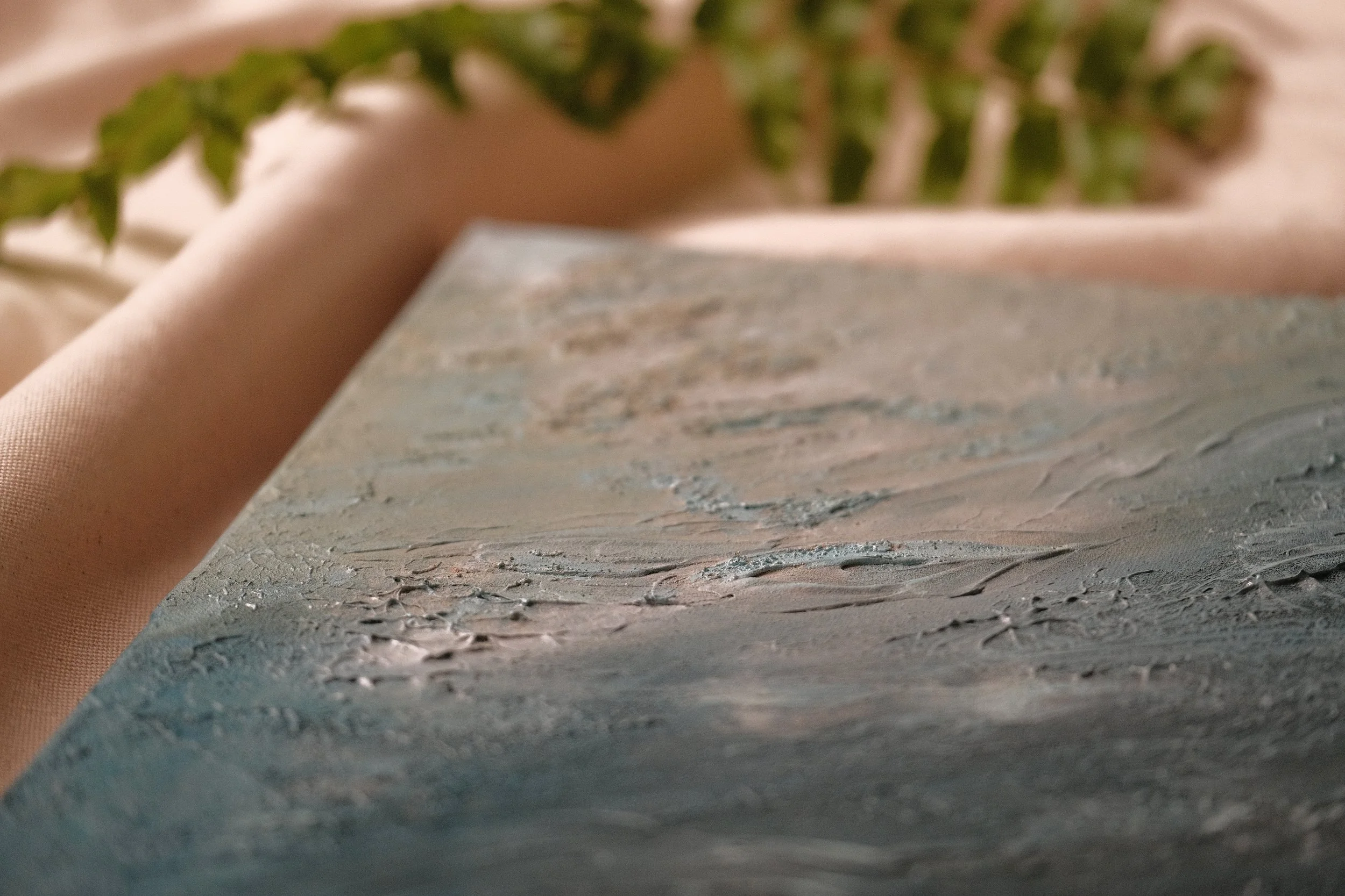Close-up of textured paint or plaster surface with a partially blurred background and another textured surface in the foreground.
