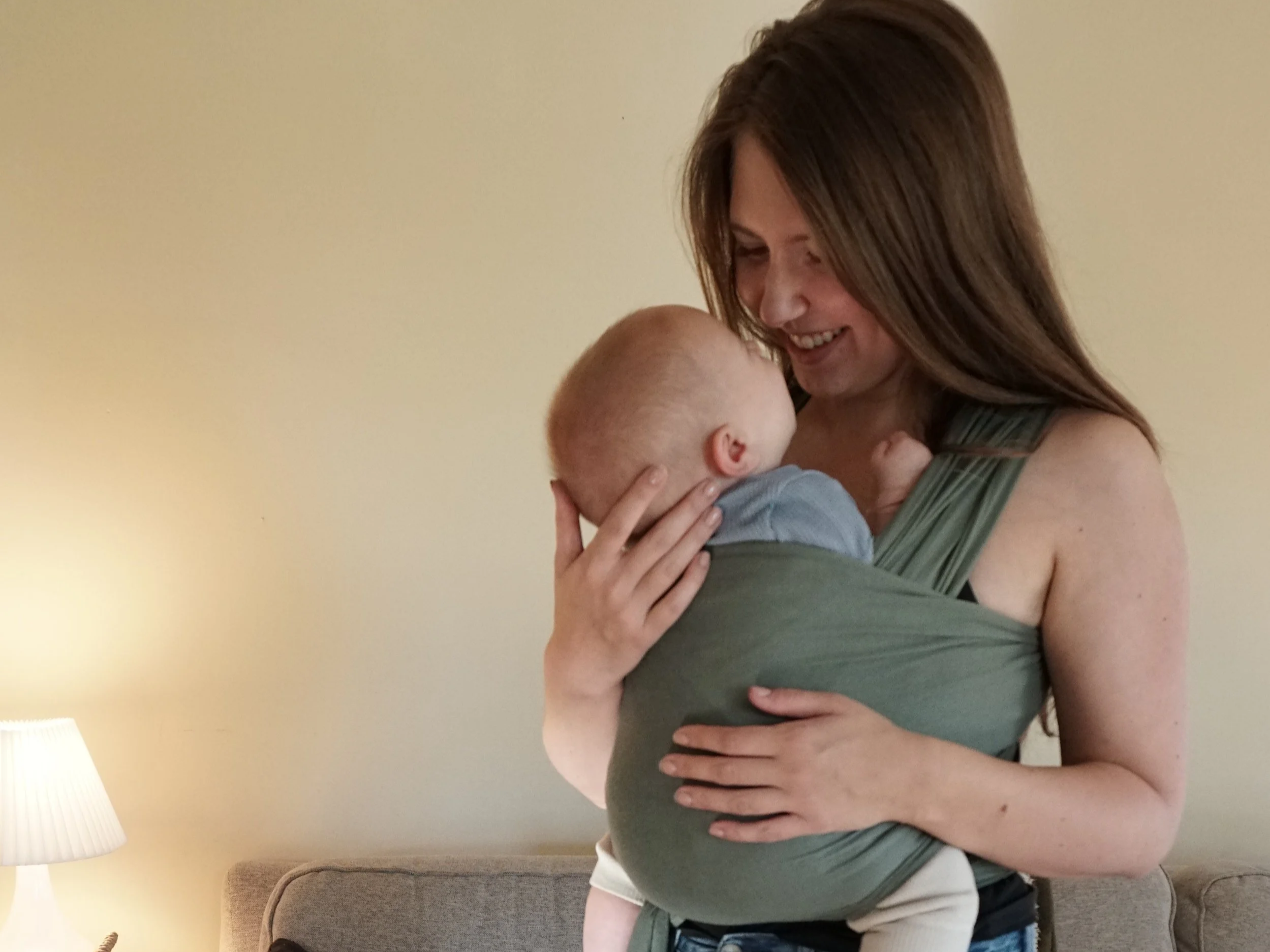 Kelsey Hughes certified babywearing educator teaching a client how to put on a Solly stretchy wrap during an in-home babywearing session in Metro Detroit
