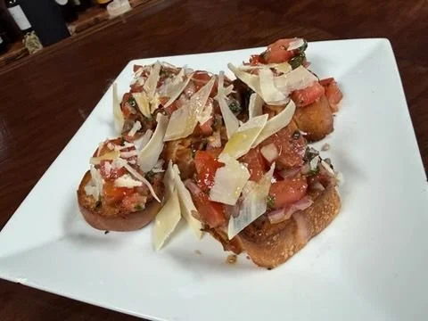 Plate of loaded potato skins topped with cheese, bacon bits, tomatoes, and onions.