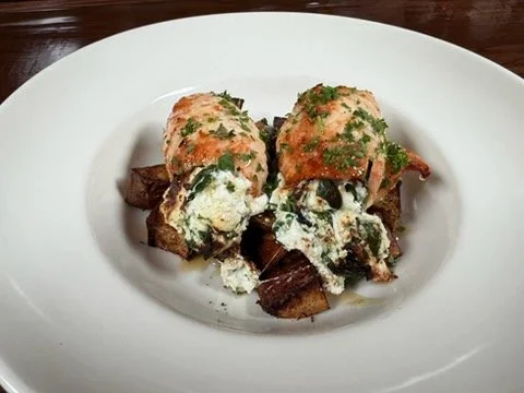 Eggs Benedict with hollandaise sauce and herbs on toasted bread with breakfast potatoes.