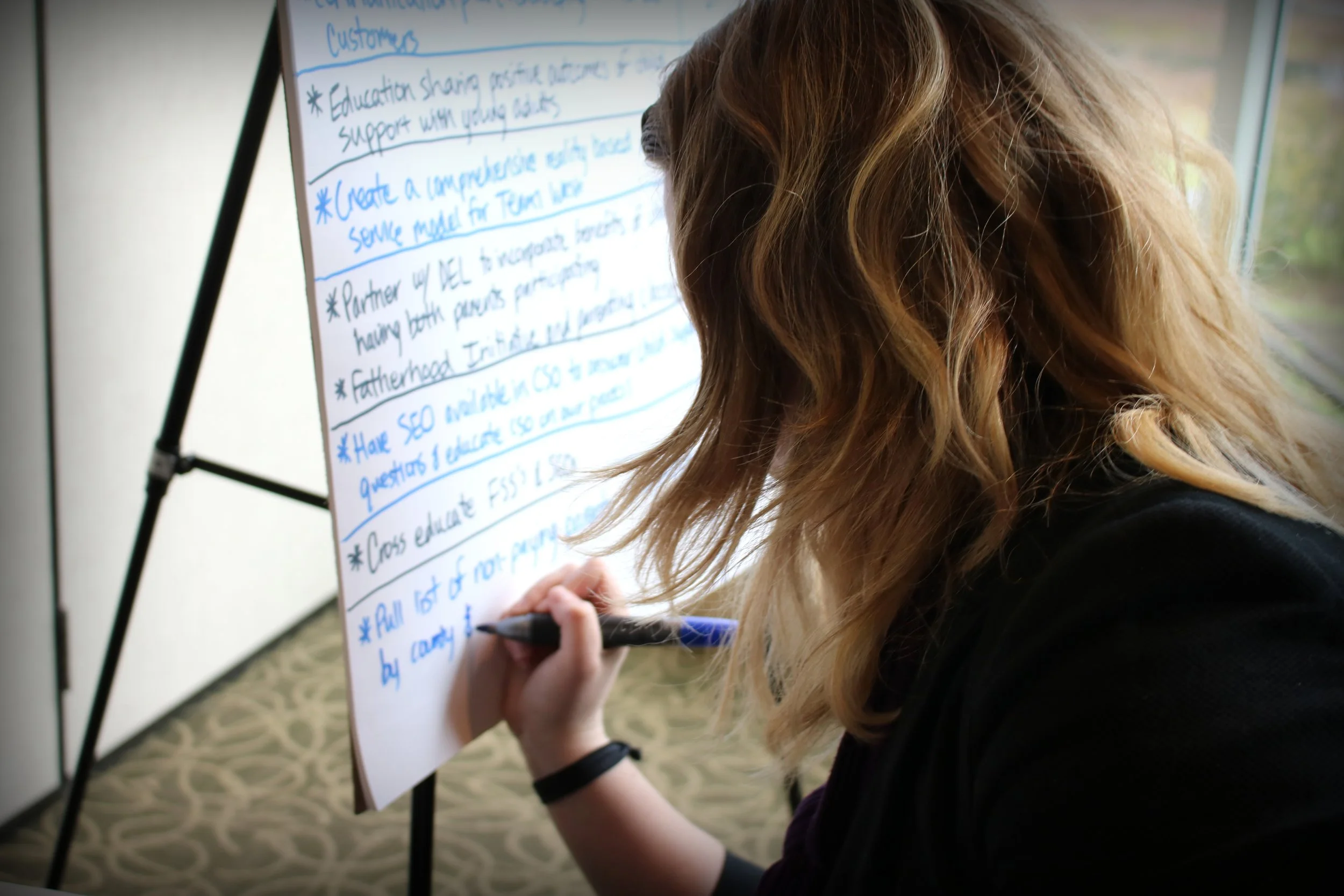 Woman writing on flip chart paper in a meeting.