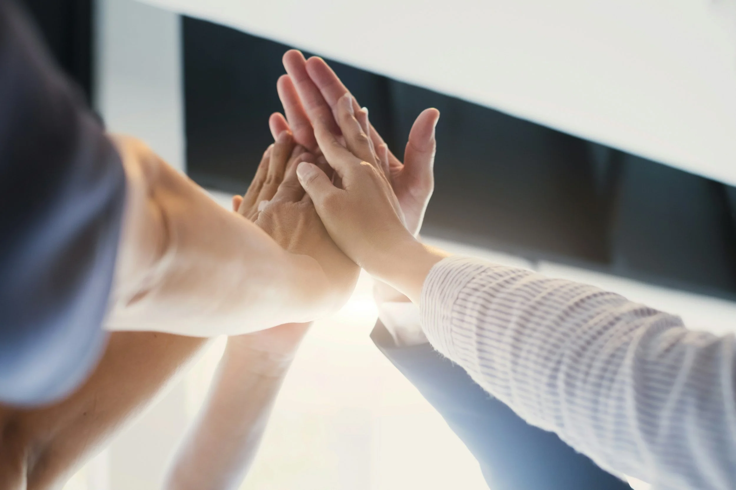 Two people are giving each other a high-five, with their hands joined in celebration or agreement.