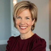 Smiling woman with short blonde hair wearing a burgundy top