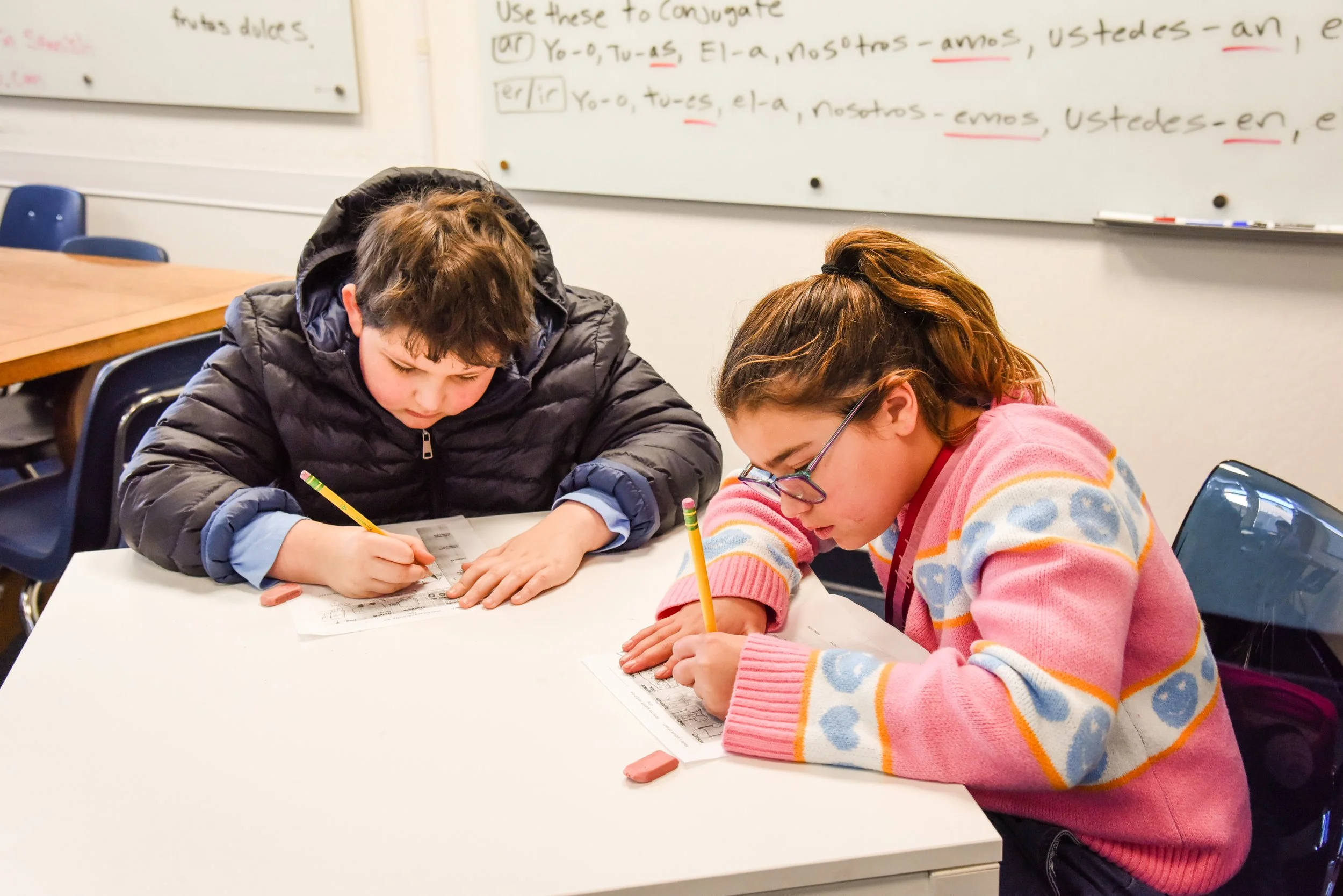 two middle school students working on a class assignment using pencil and eraser.