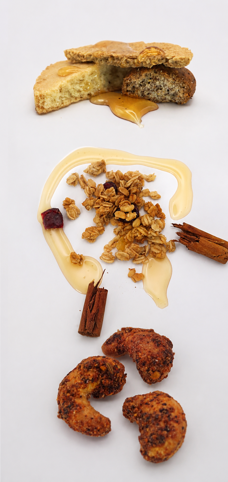 Three distinct snack items on a white background: sliced peanut butter cookies with caramel drizzled on top, a cluster of granola with dried berries and nuts surrounded by a swirl of white chocolate, and a handful of crispy, spiced fried chicken pieces.