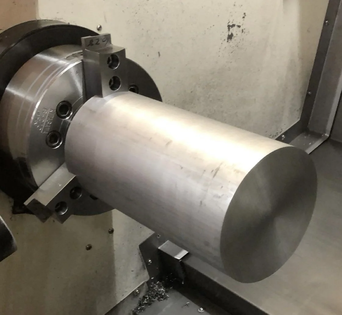 A cylindrical metal workpiece mounted on a lathe machine.
