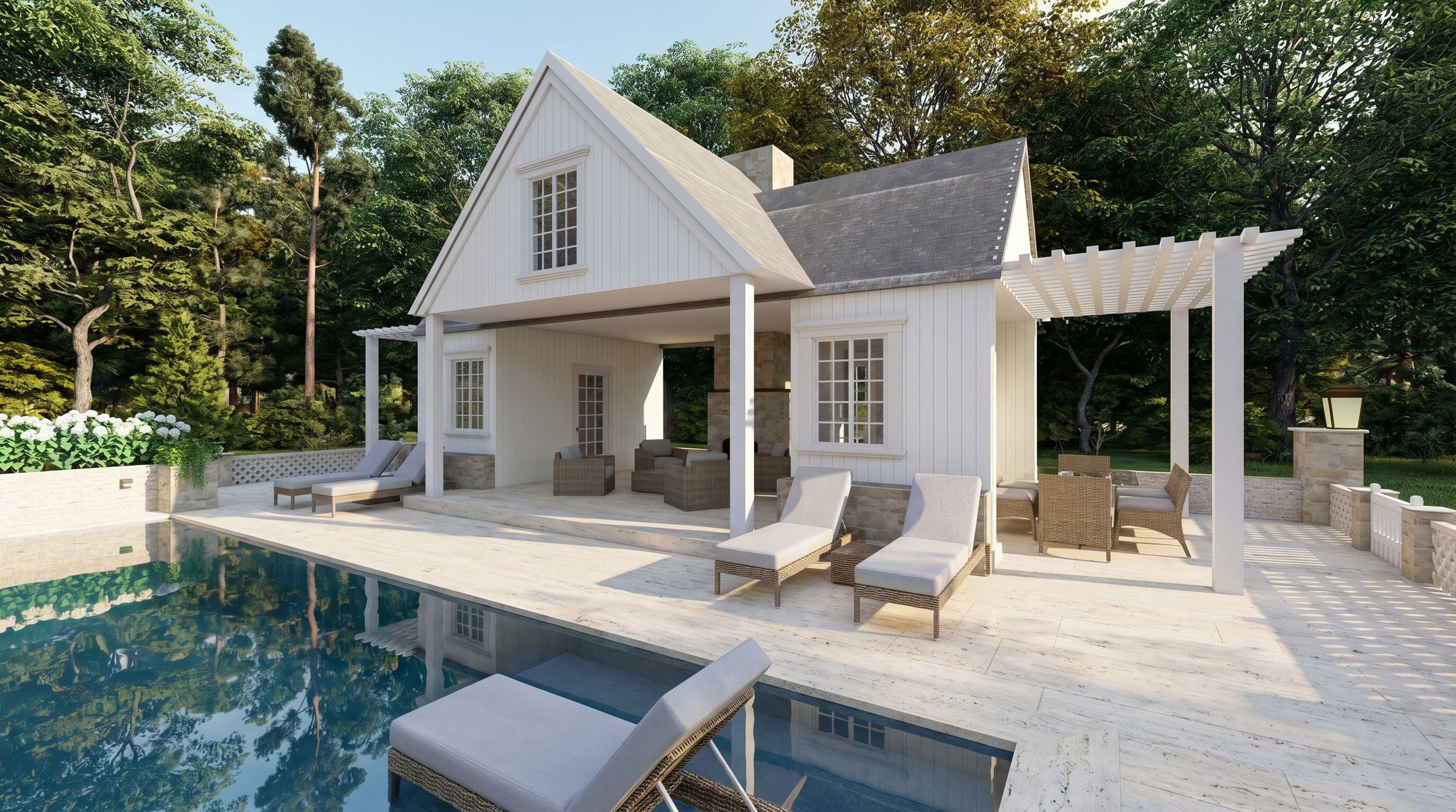 A white house with a steep gabled roof and large windows, situated near a swimming pool with lounge chairs and outdoor furniture, surrounded by lush green trees.