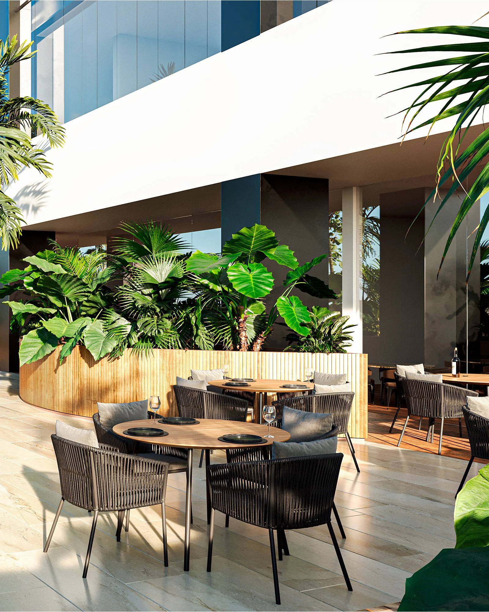 Restaurante con mesas y sillas de mimbre, decorado con plantas verdes y vegetación en un espacio abierto y moderno.