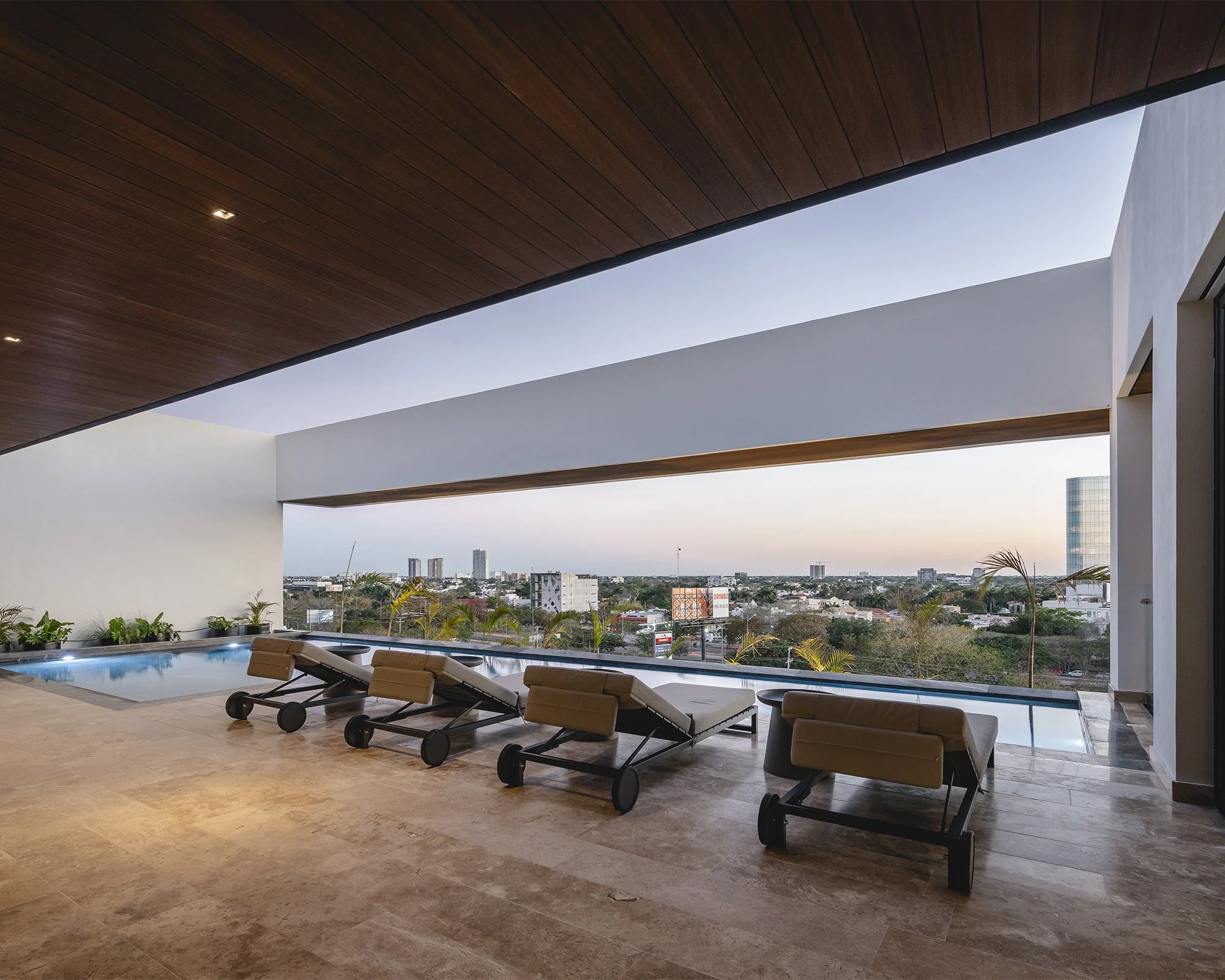 Ático moderno con piscina en la terraza, tumbonas de diseño, vista panorámica de la ciudad y cielo despejado.