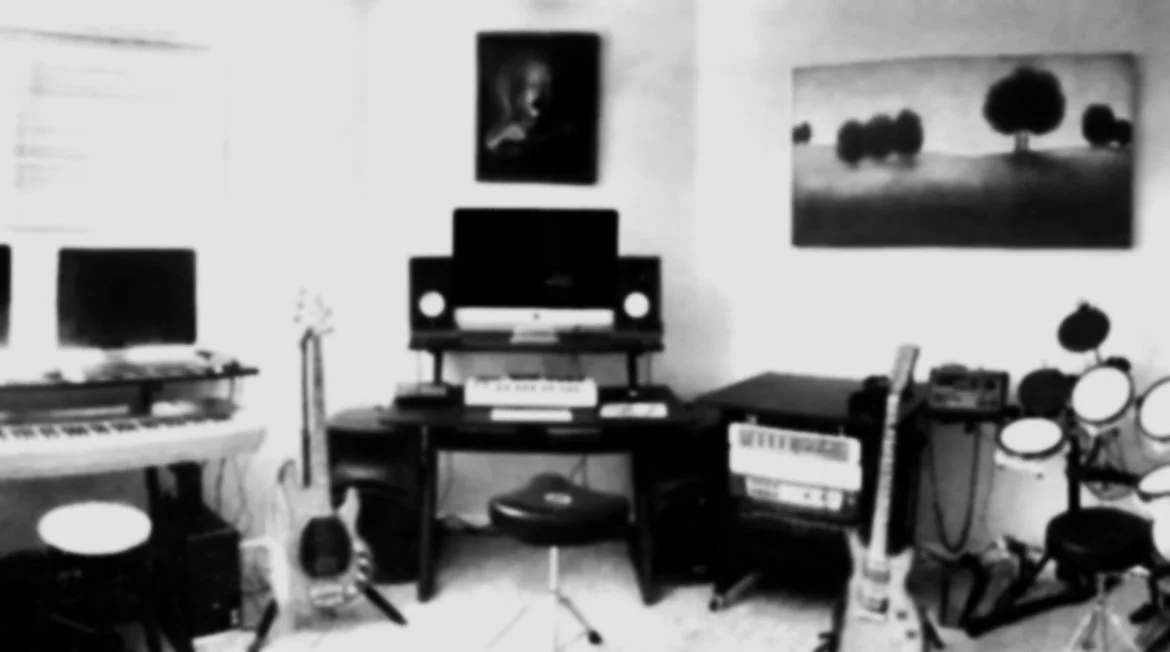 Photo of a music studio with musical instruments, studio equipment, and computers on desks.