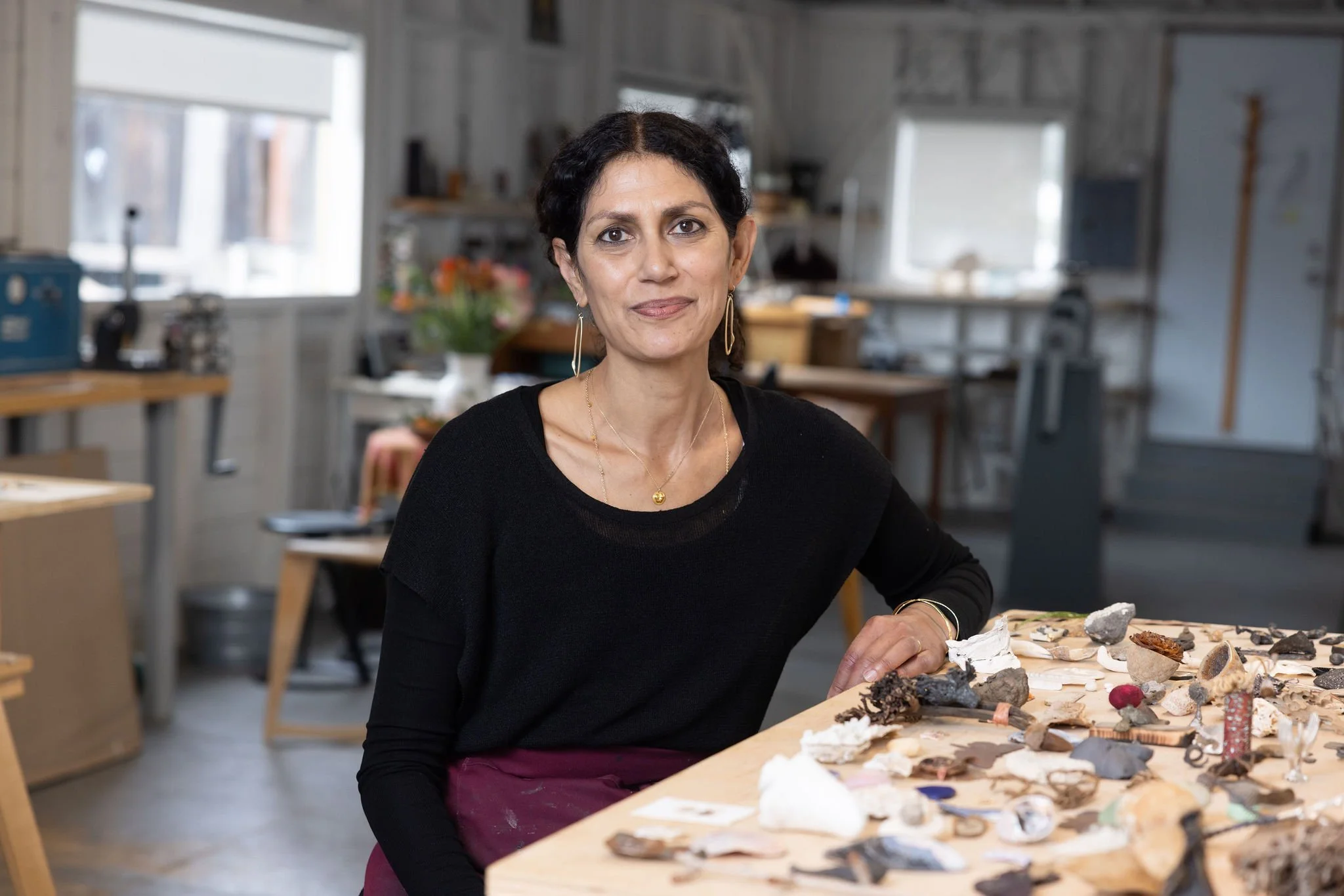 Maya KIni seated in front of her collections of natural objects that inspire her practice.