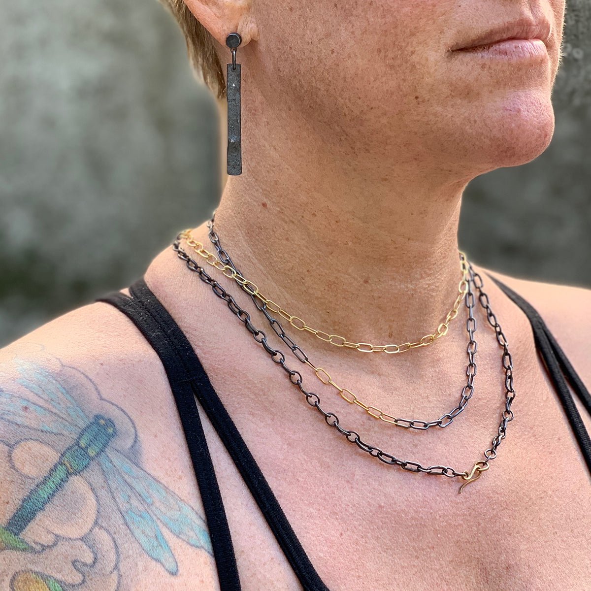 model wearing layered oxidized silver and 18k gold handmade chains