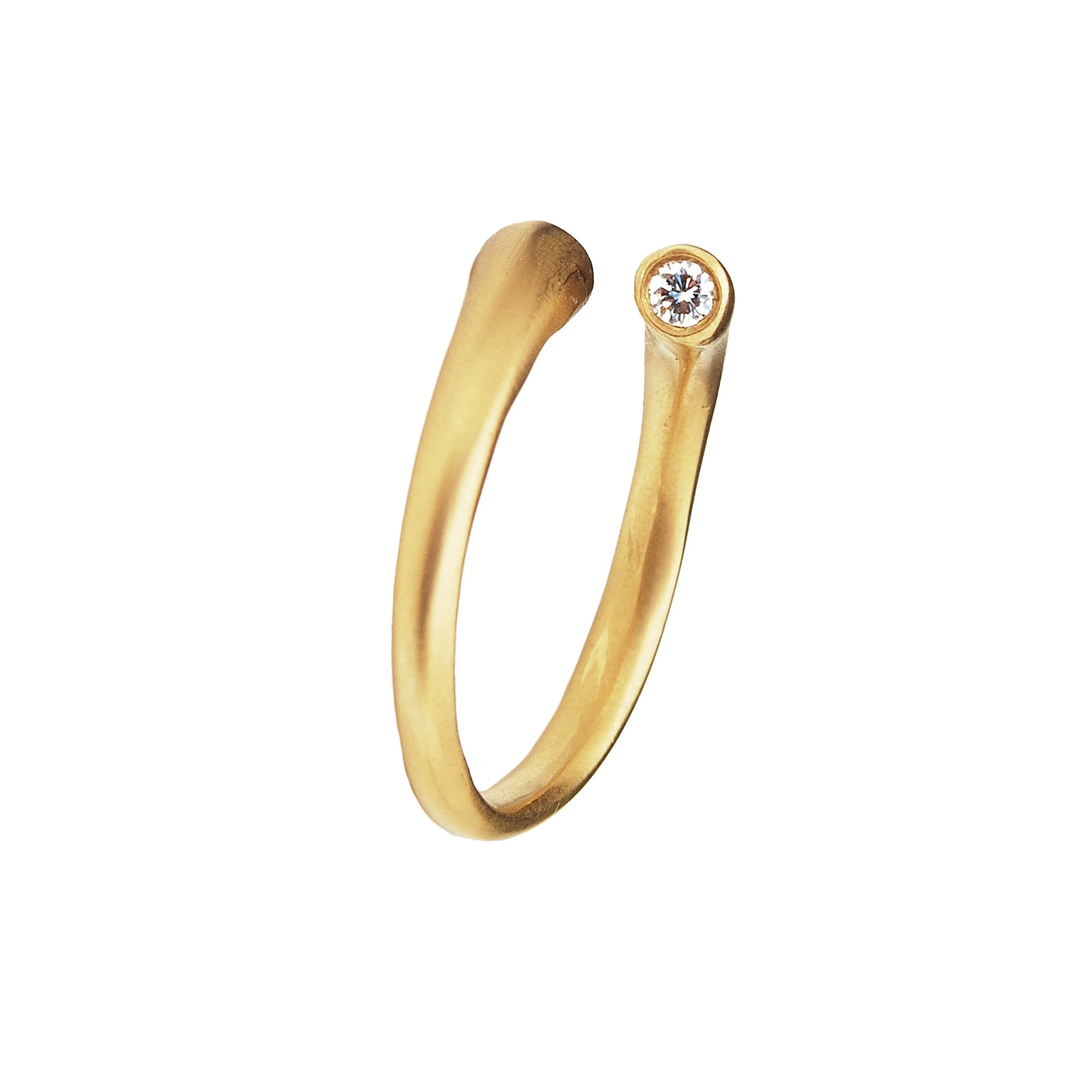 Close-up of a gold earring with a single sparkling gemstone.