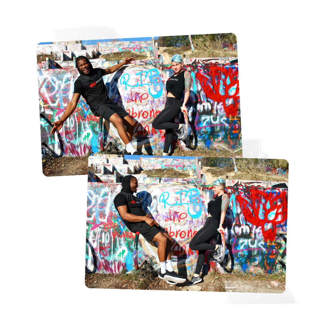 Two people, a man and a woman, appear to be on a graffiti-covered wall. The man is sitting and the woman is standing, both are posing playfully, holding hands.