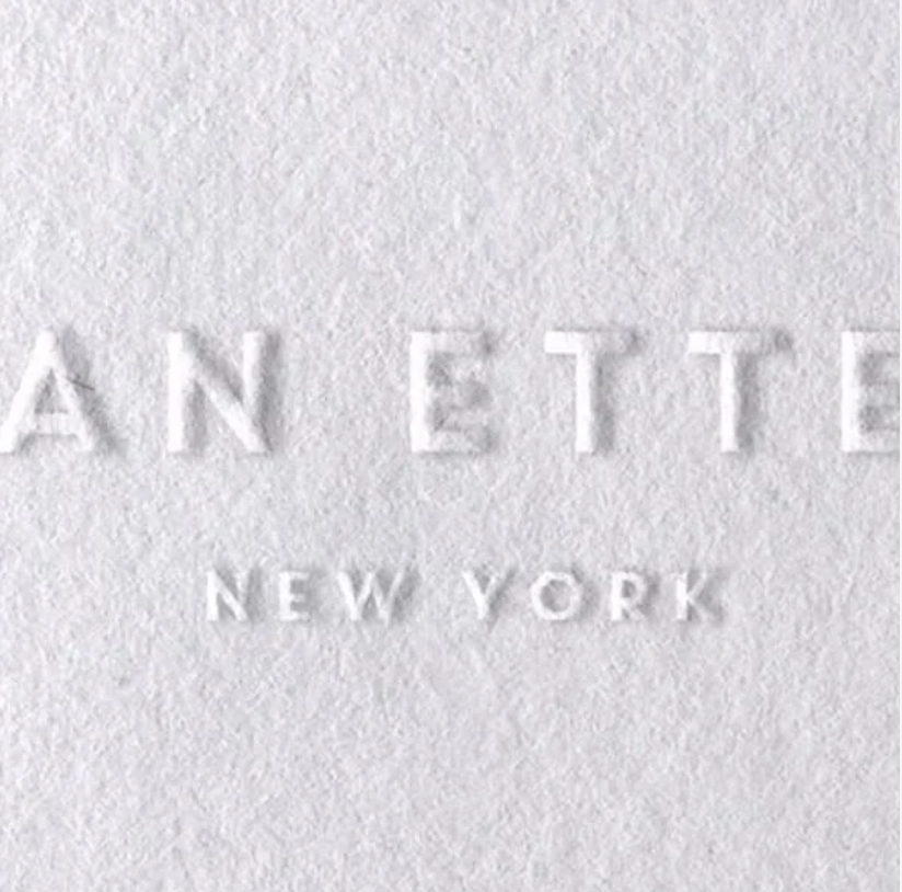 The word 'ATTEN' and 'NEW YORK' are embossed on a white textured surface, likely a wall or paper.
