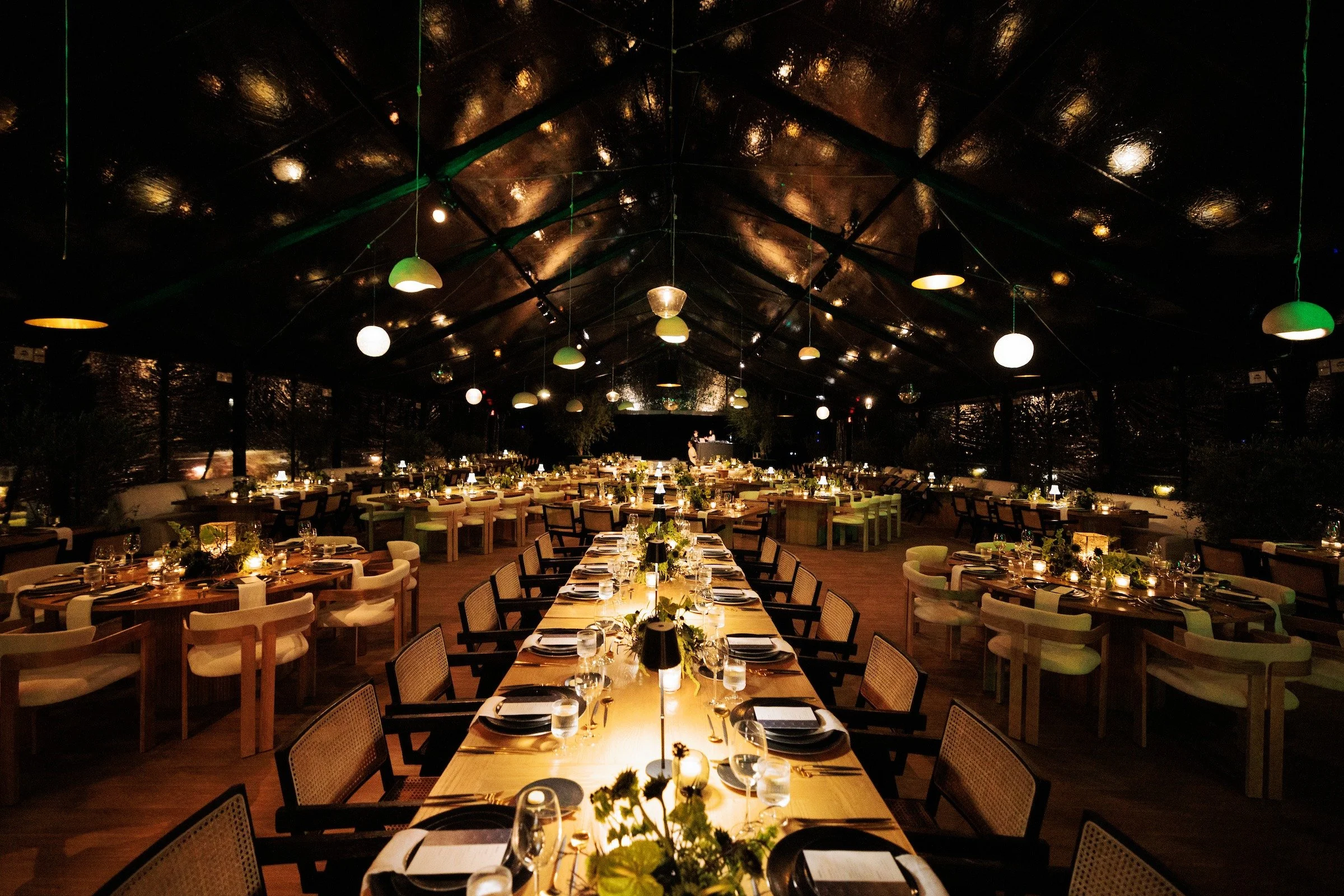 Long luxury banquet dinner table with pendant lighting inside elegant event tent — Grove Projects