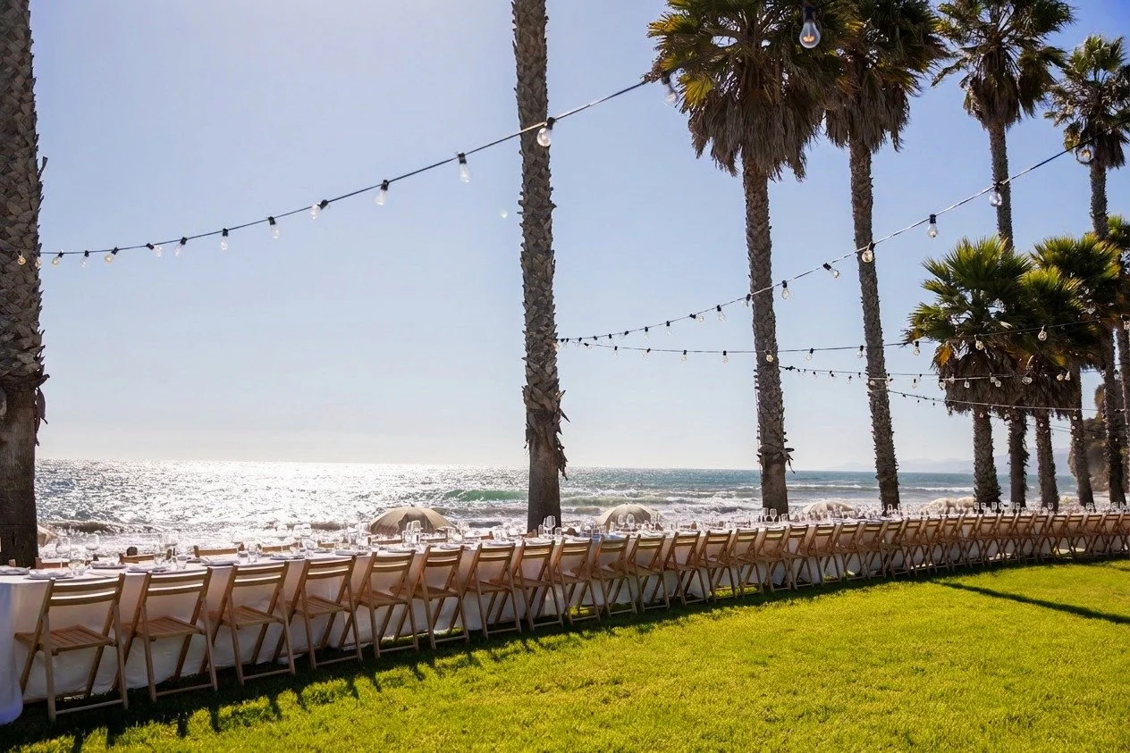 Beachside outdoor event setup with string lights and ocean views — Grove Projects