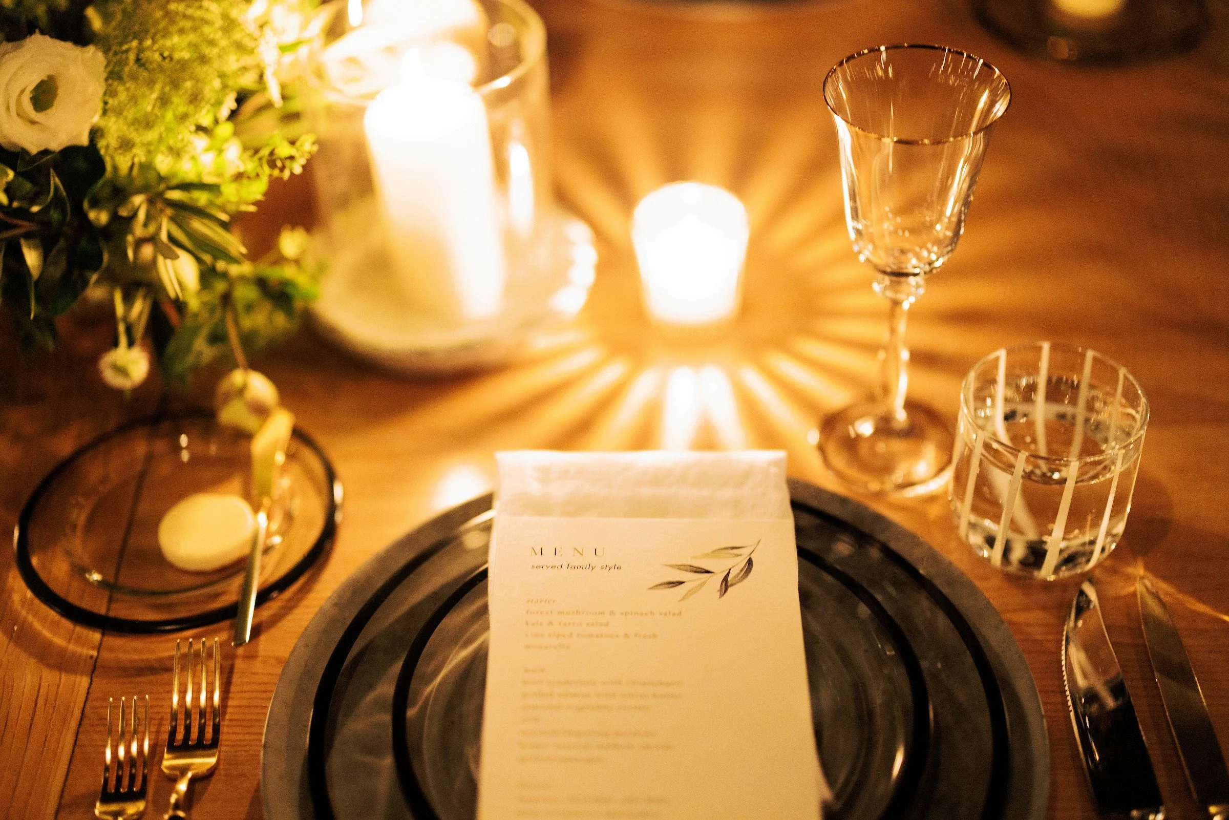 Candlelit luxury dinner place setting with crystal glassware and menu card — Grove Projects