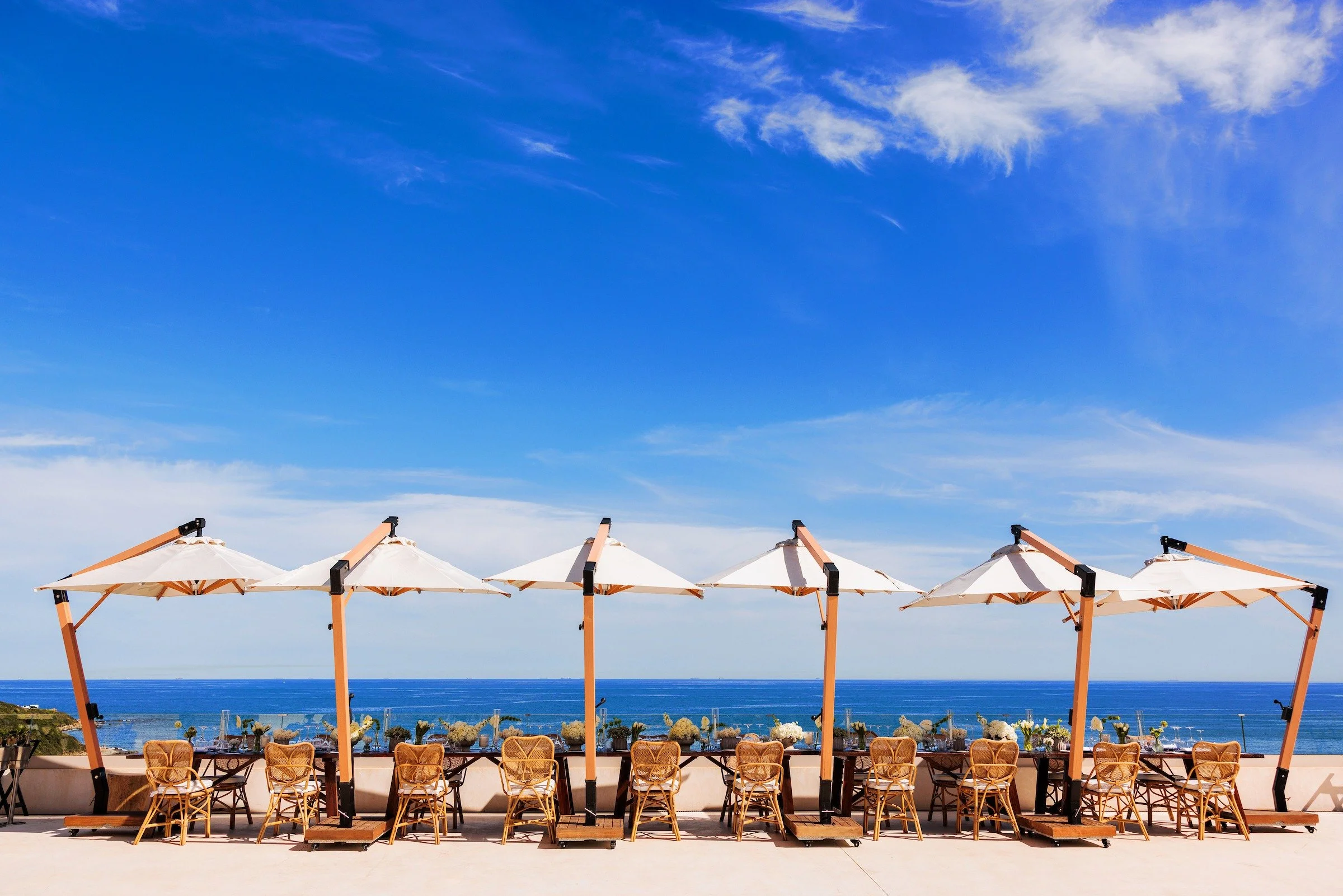Outdoor luxury event setup with white umbrellas and ocean views, Costa del Sol Spain — Grove Projects