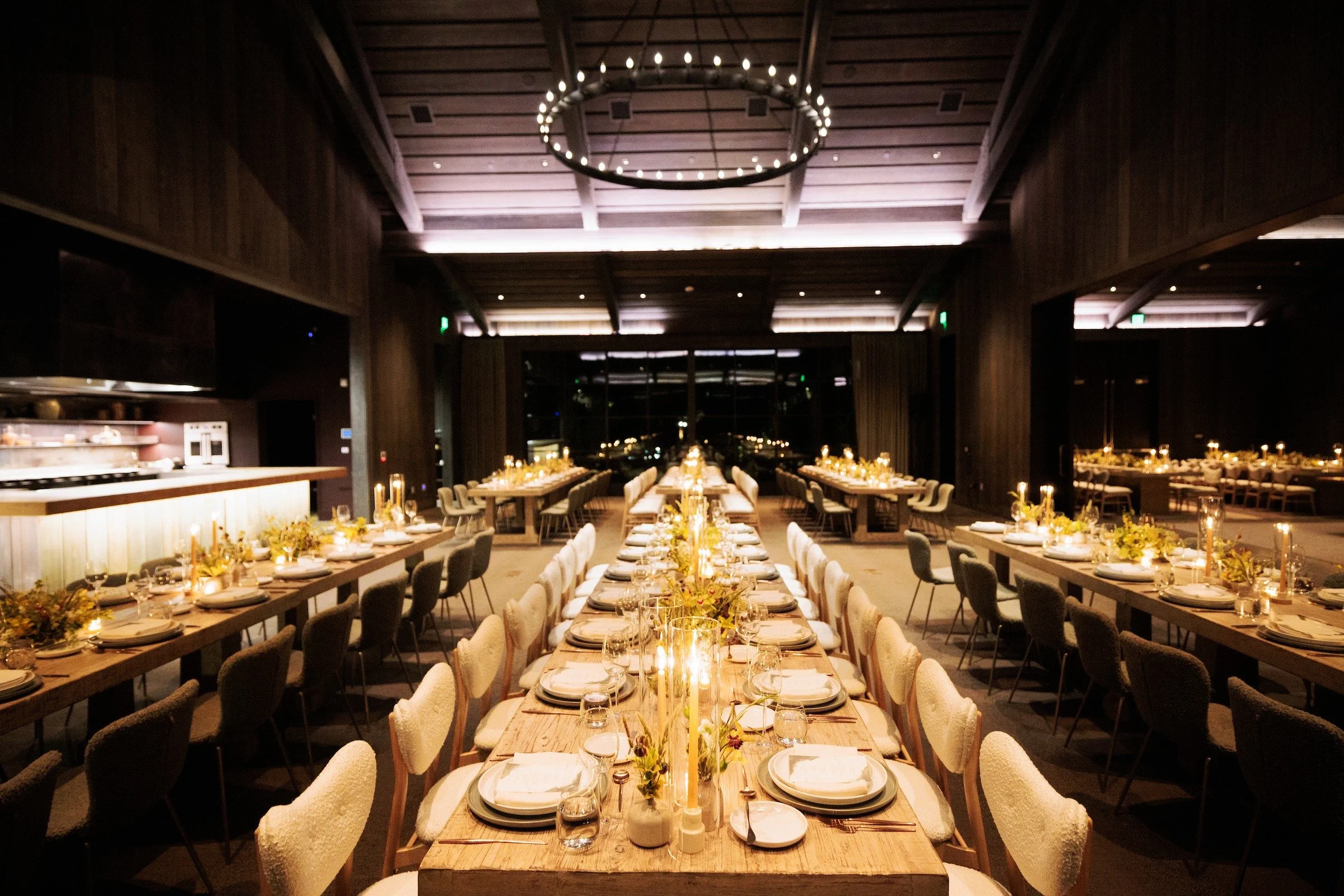 Long banquet dinner table with warm lighting inside rustic luxury event venue — Grove Projects