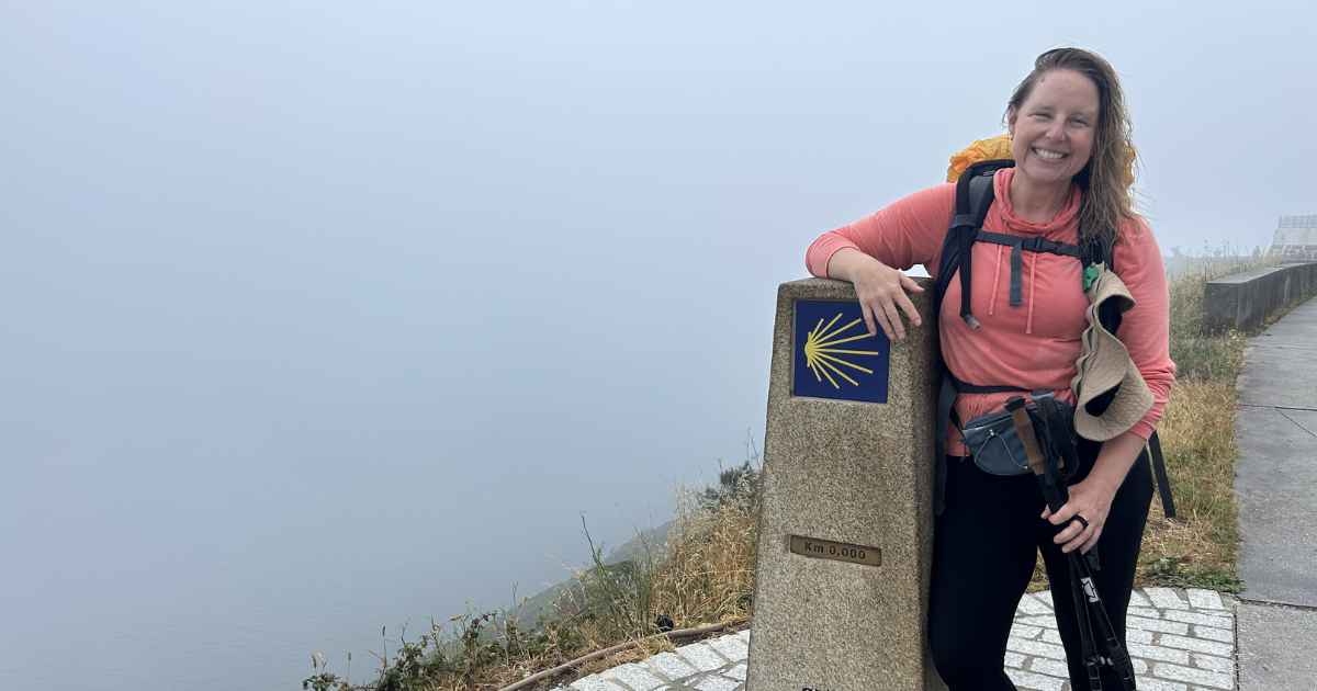 Andrea at the end of the camino smiling with the 0km marker