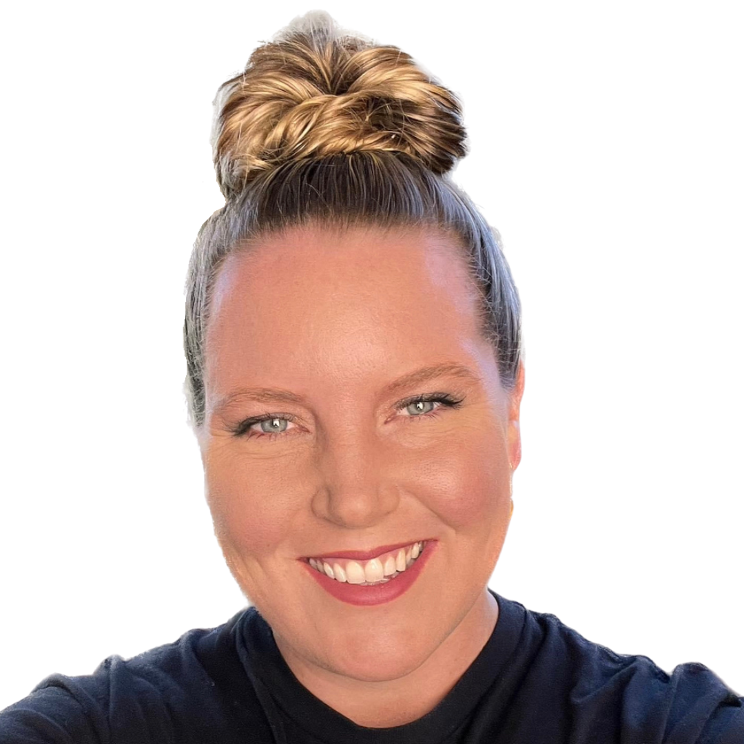 A client of Andrea Tessier, life coach. Close-up of a woman with blonde hair tied in a top bun, smiling at camera, wearing a black top, with a plain white background.