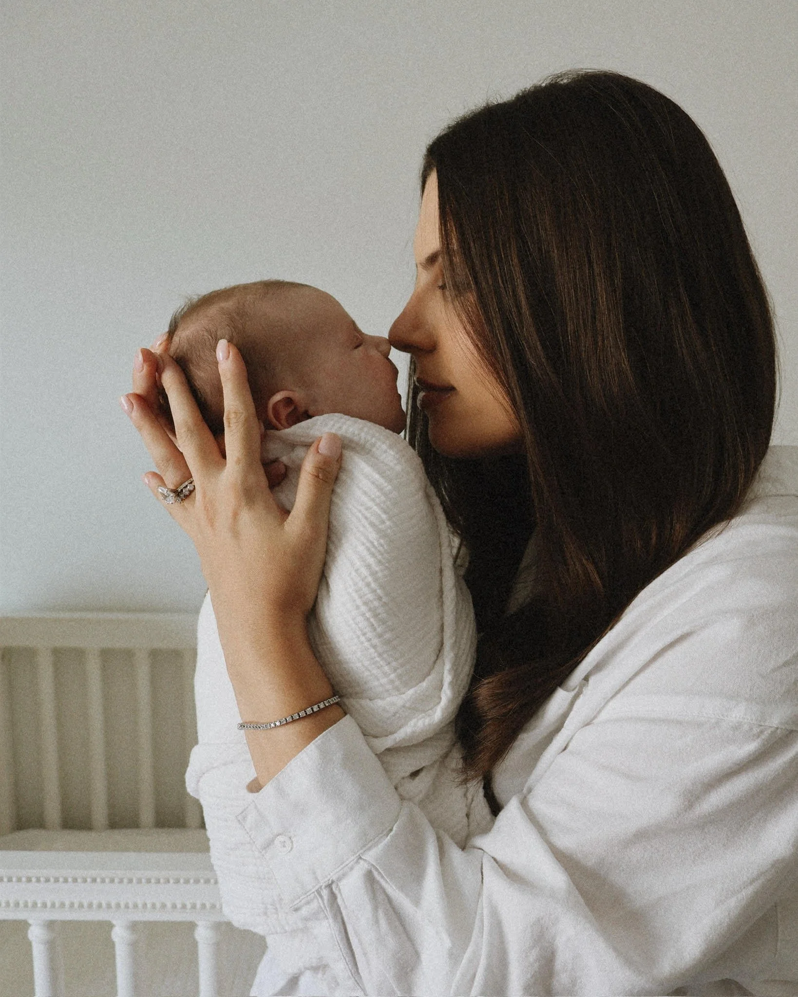 A woman holding a baby close to her face, with their noses touching, in an intimate moment.