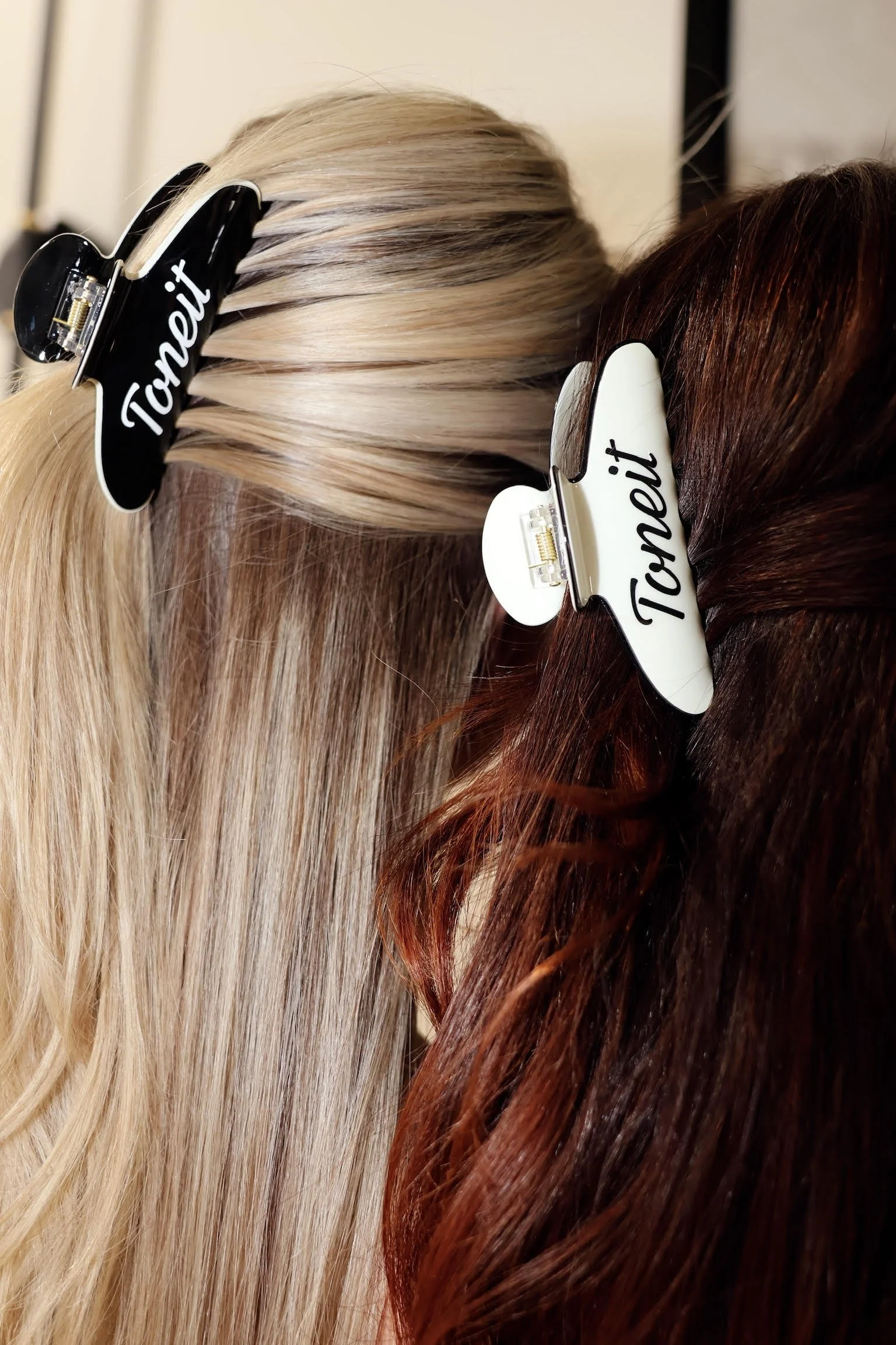 Close-up of three wig hairpieces with different shades: platinum blonde, medium brunette, and deep red, each with a 'Tonet' label clip.