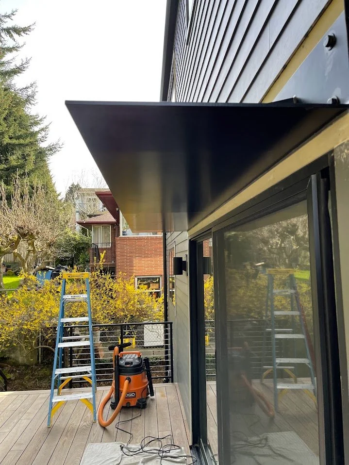 A house exterior with a wooden deck, ladder, and vacuum cleaner, reflecting a cleaning or maintenance activity.