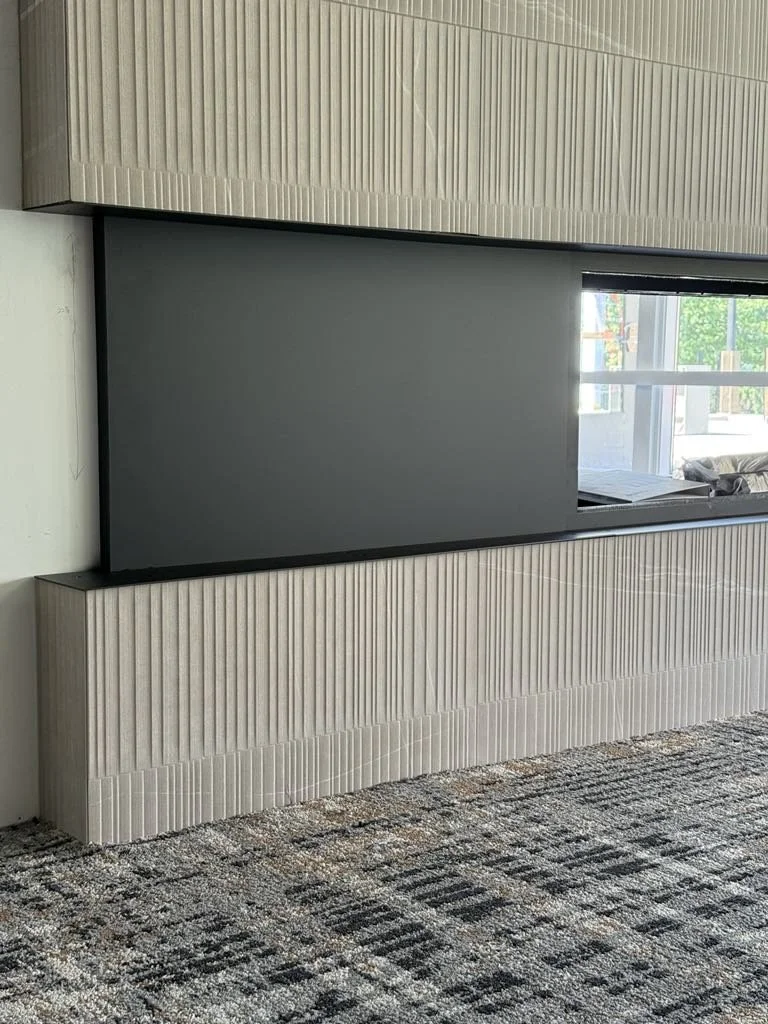 Modern interior with a TV mounted on a textured wall, window with outdoor view, and carpeted floor.