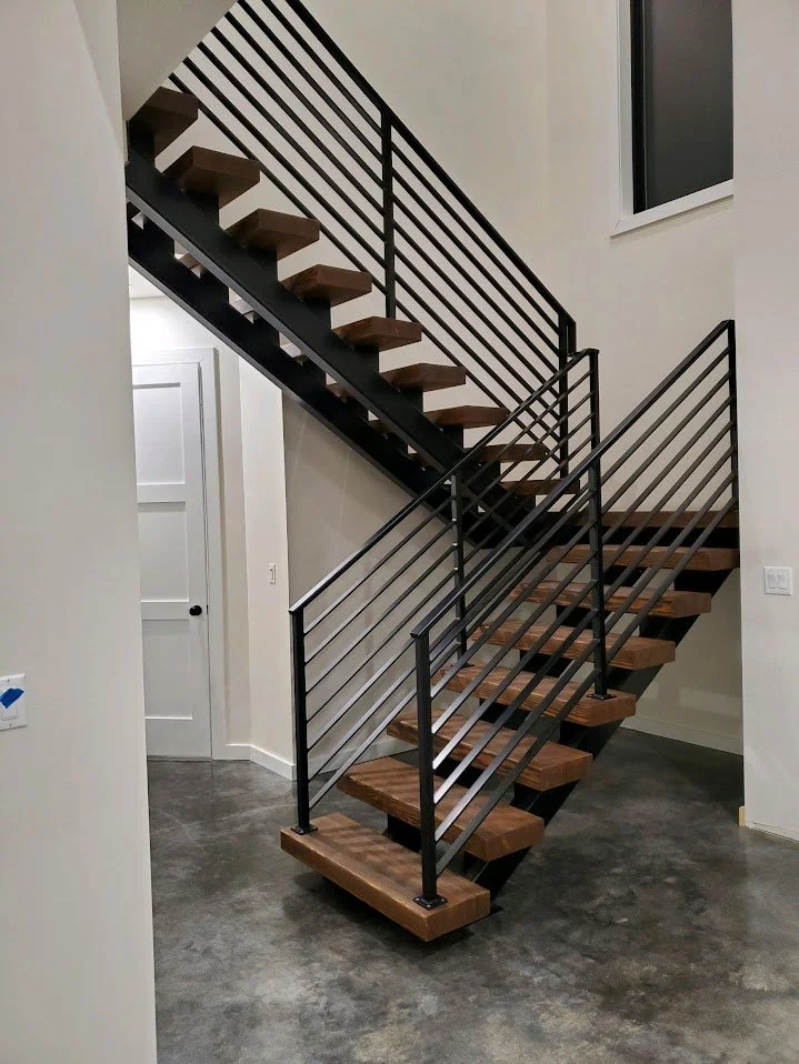A modern staircase with wooden steps and black metal railings inside a home.