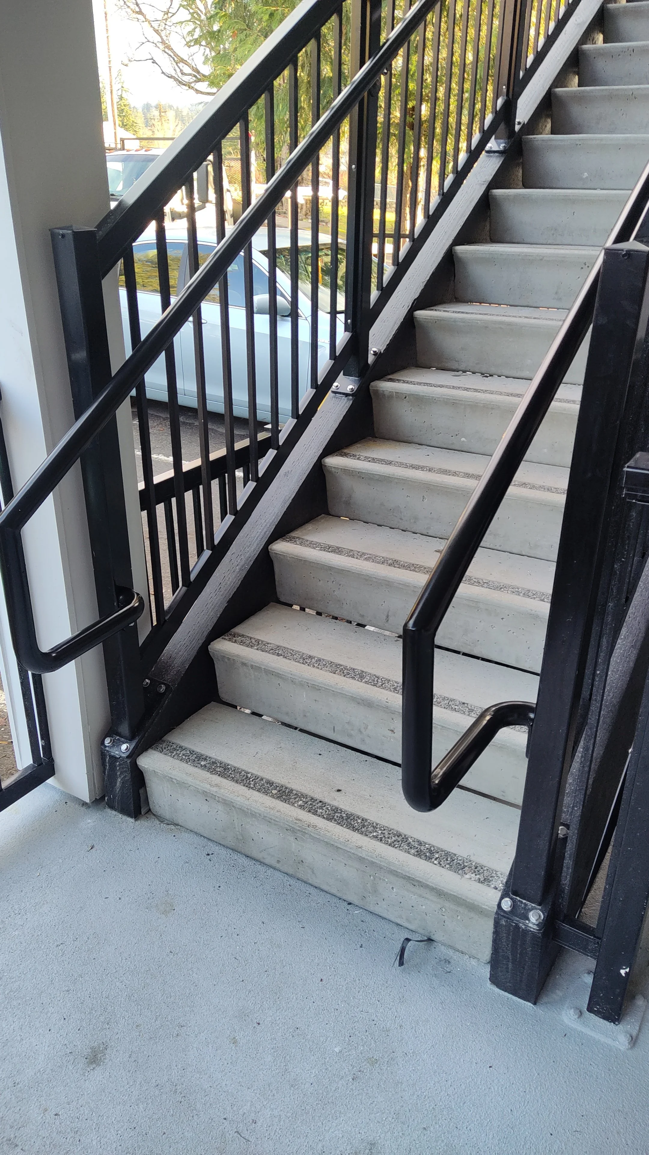 Exterior stairway with black metal railing and concrete steps leading to an upper level.