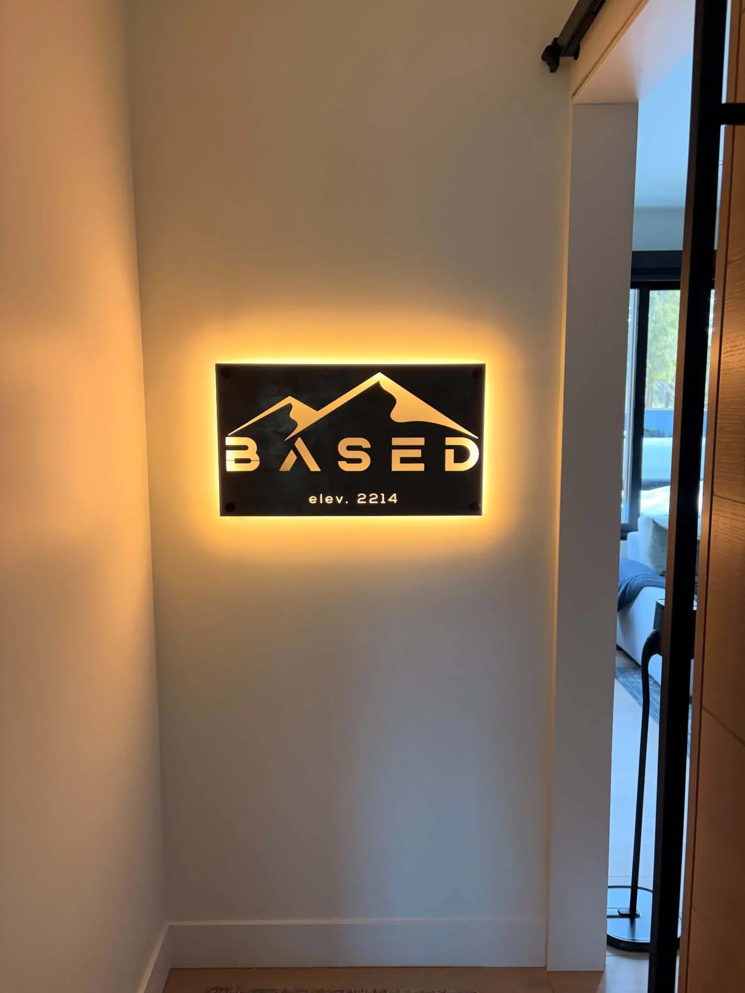 Decorative sign with mountain design and the word 'BASERD' illuminated on a wall, with an ambient glow and an elevation of 2214.