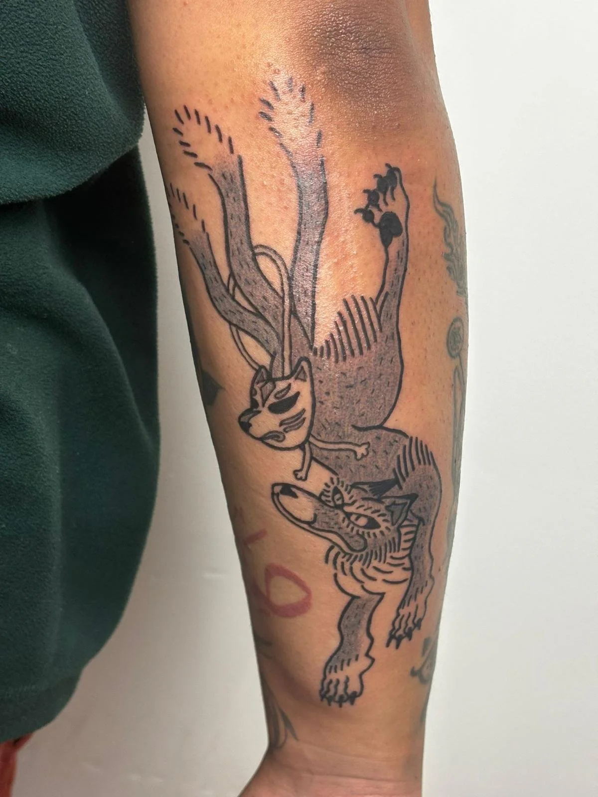 Tattoo of a whimsical animal hybrid on person's arm, featuring a lion's head with a stern expression and a squirrel's body with bushy tail, drawn in black ink with line art style.