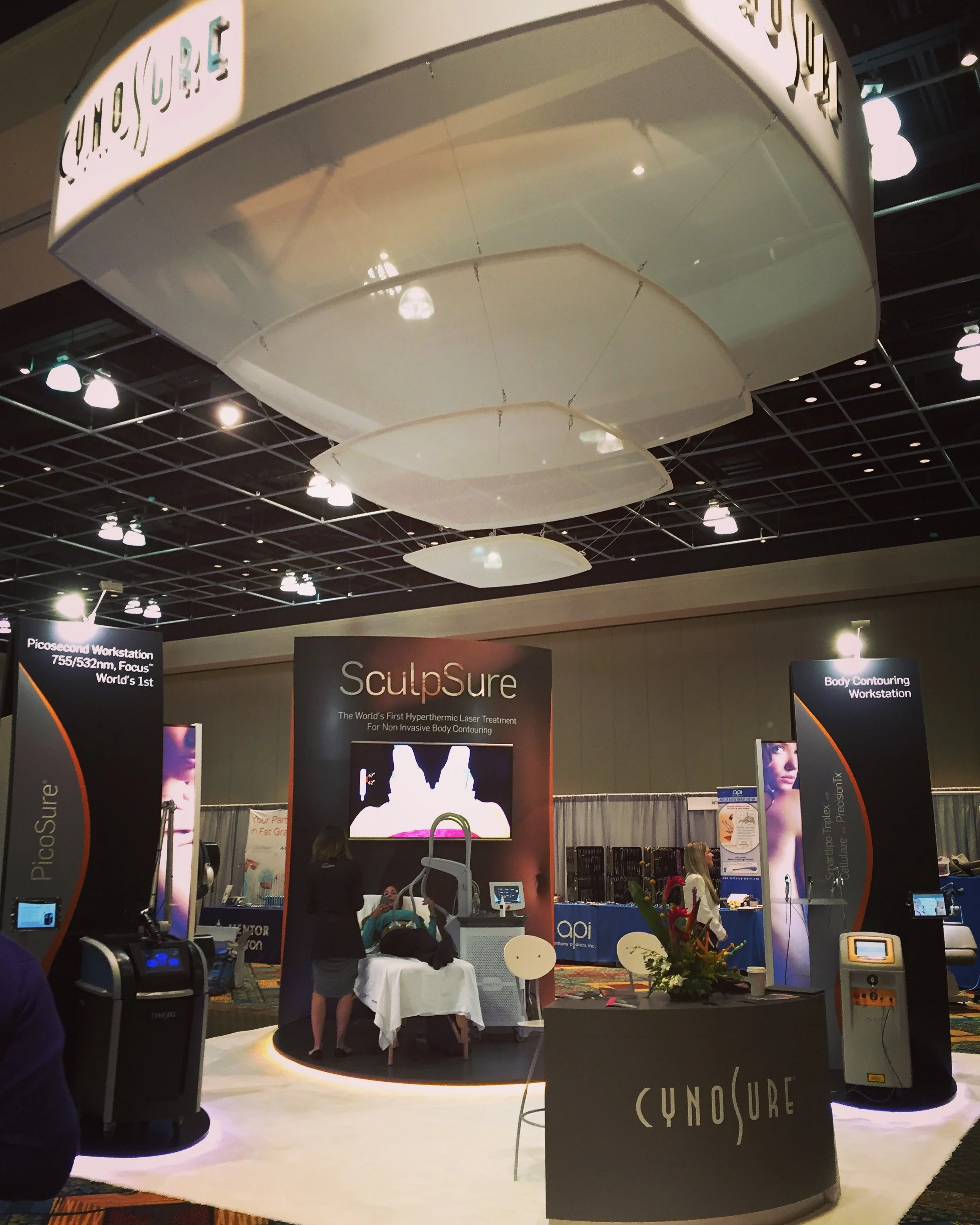 Trade show booth for SculpSure, a non-invasive body contouring laser treatment, with banners, displays, and vendors.