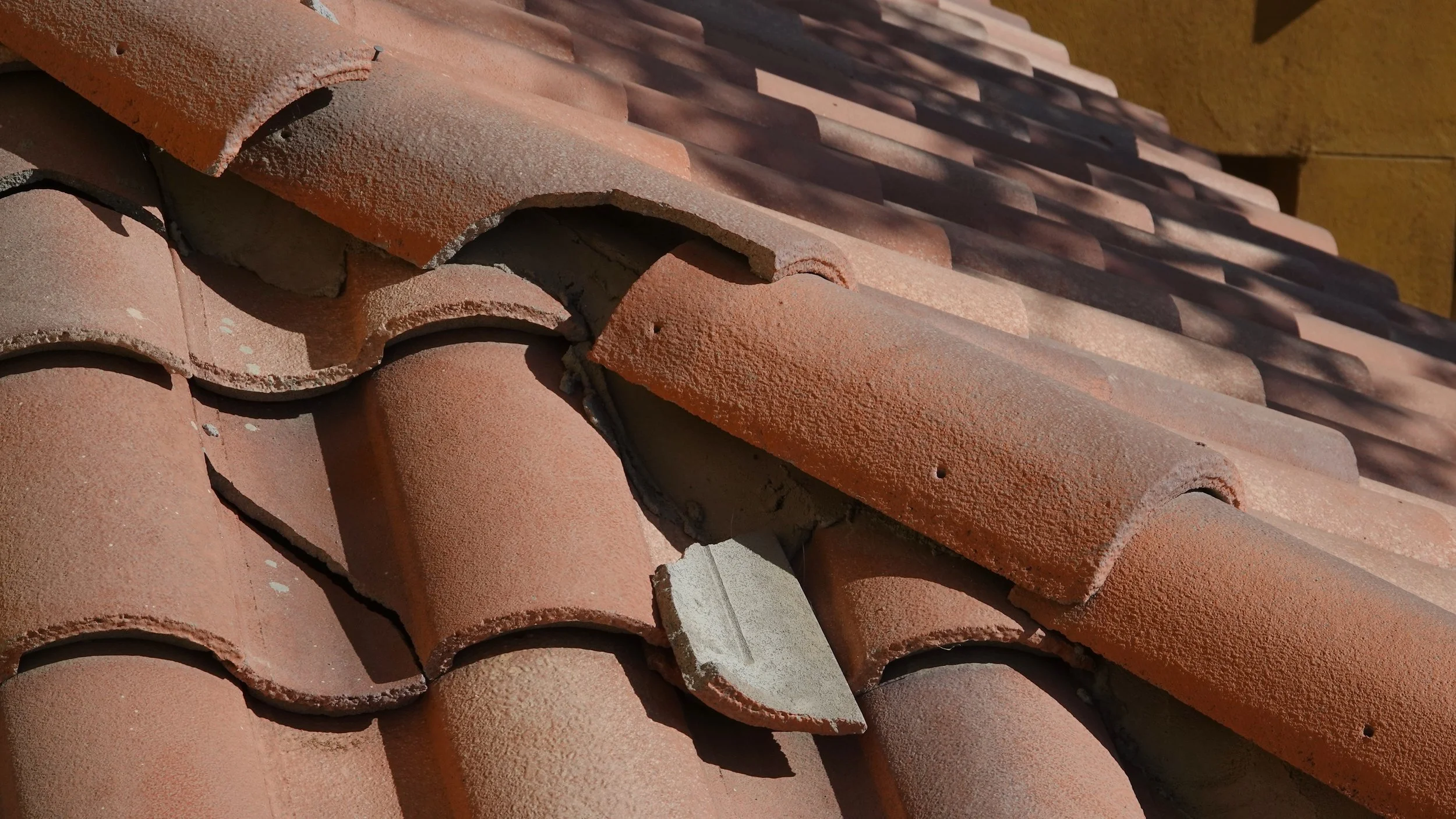 Stack of curved, reddish-orange roof tiles on a building roof.