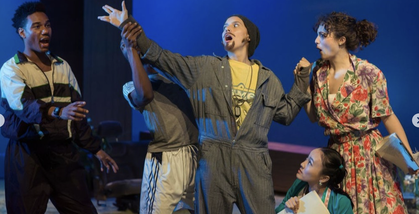 Actors performing on stage, engaged in a dramatic scene with animated expressions and gestures.