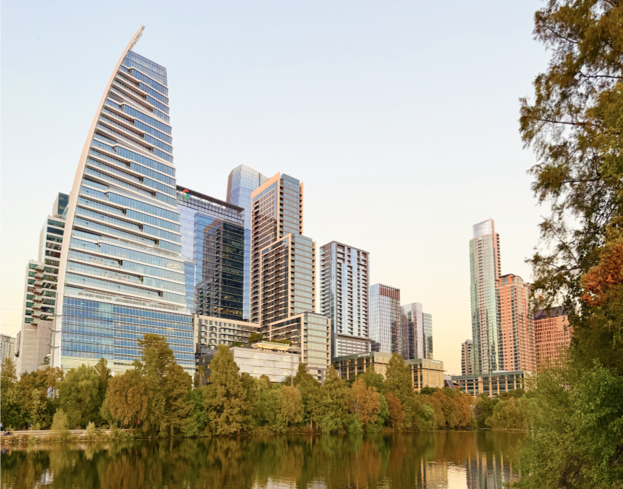 Skyscrapers and modern buildings near a body of water with trees in urban downtown area during daytime