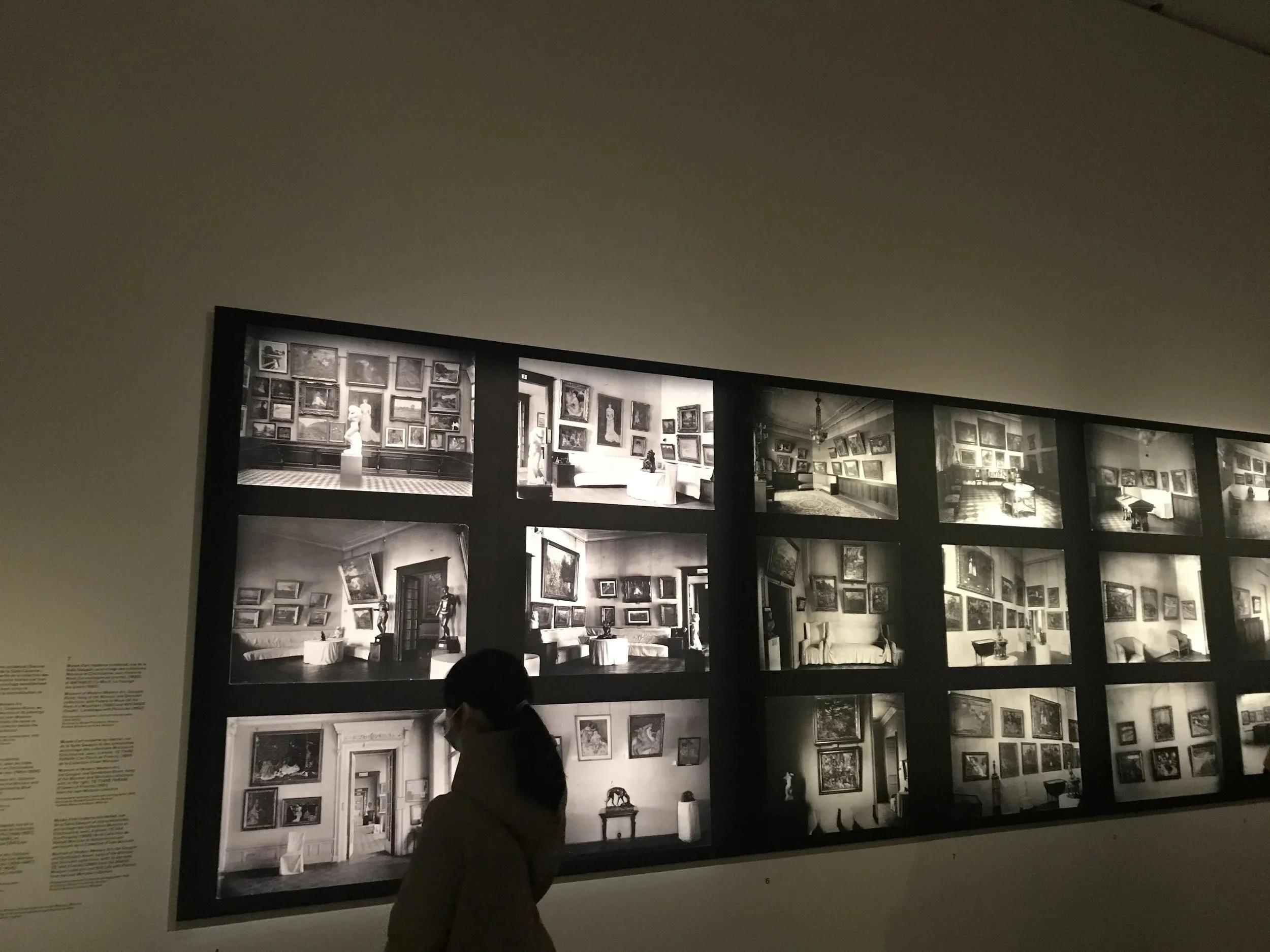 Une personne regarde une grande affiche de plusieurs œuvres d'art dans un musée ou une galerie.