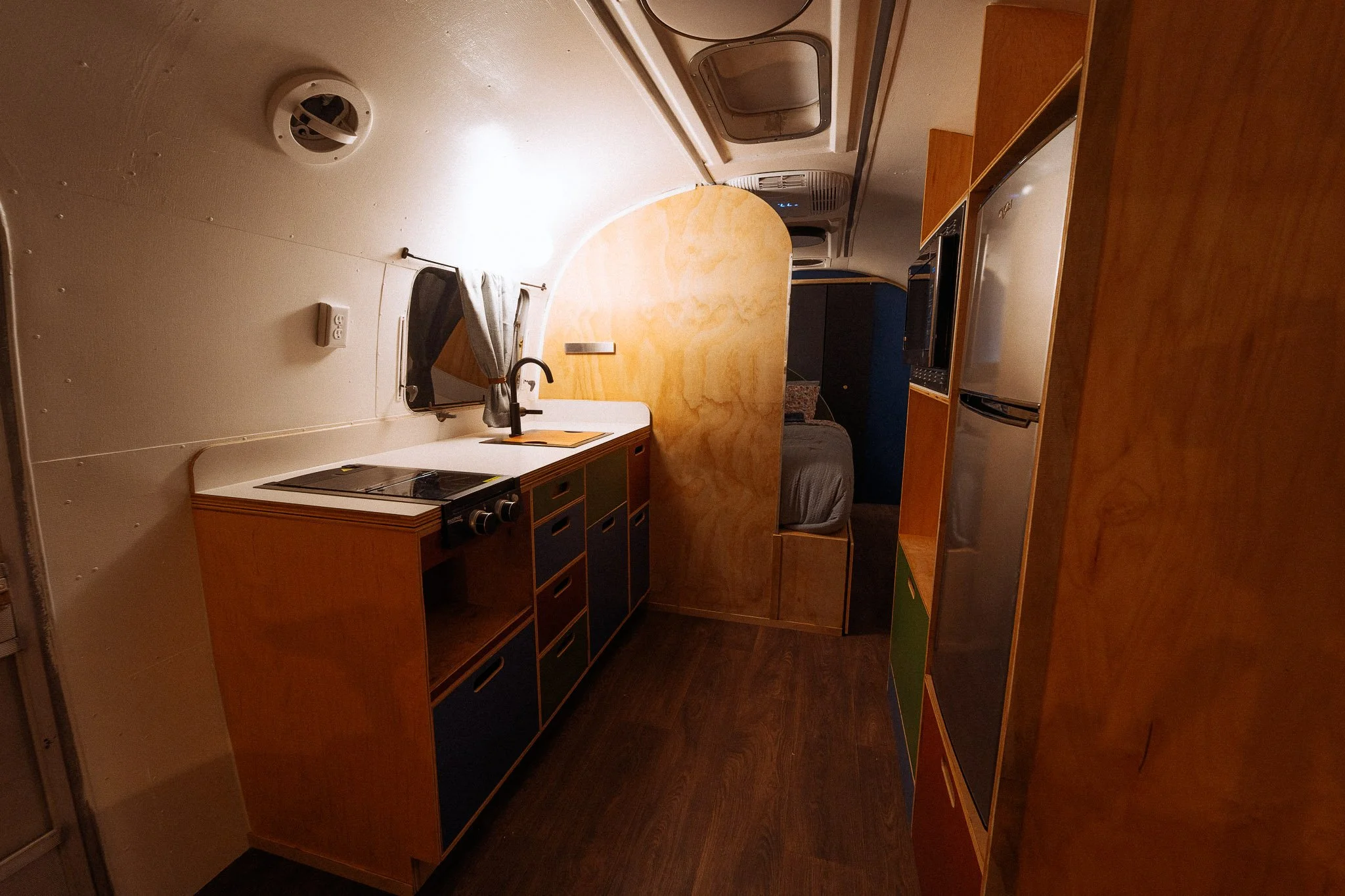Interior of a small camper or RV with a kitchen area, bed, and compact living space.