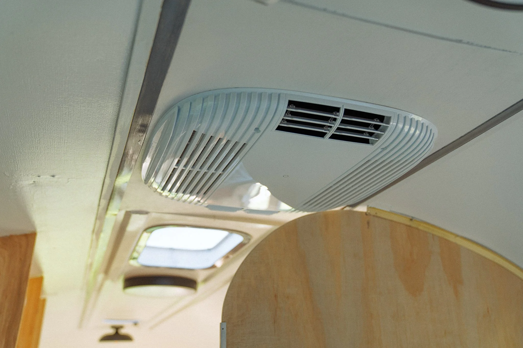Close-up of a ceiling air vent and skylight window inside a building.